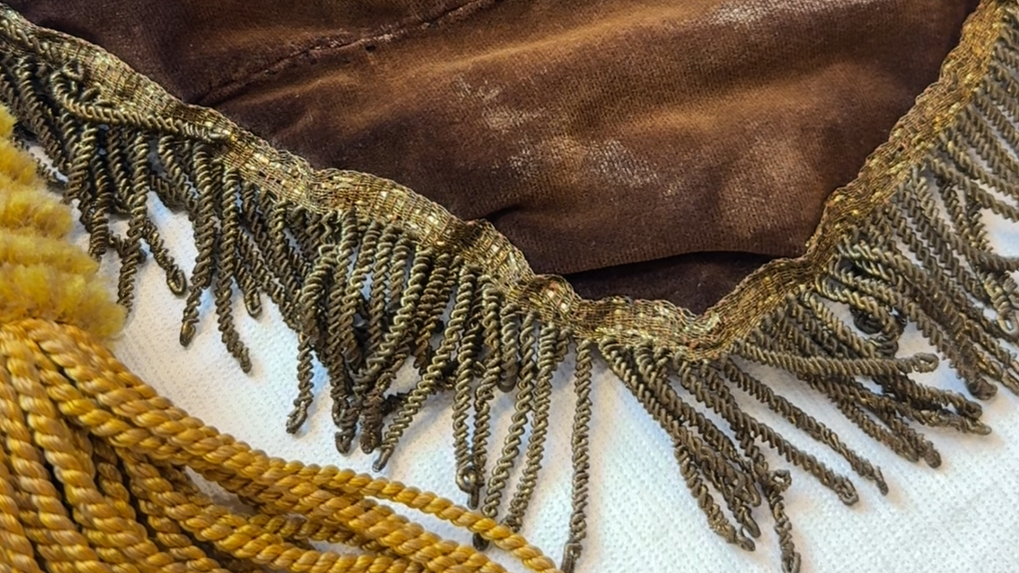 Close-up foto van een scheurtje wat weer dichtgenaaid is in het bruin-fluwele vaandel.