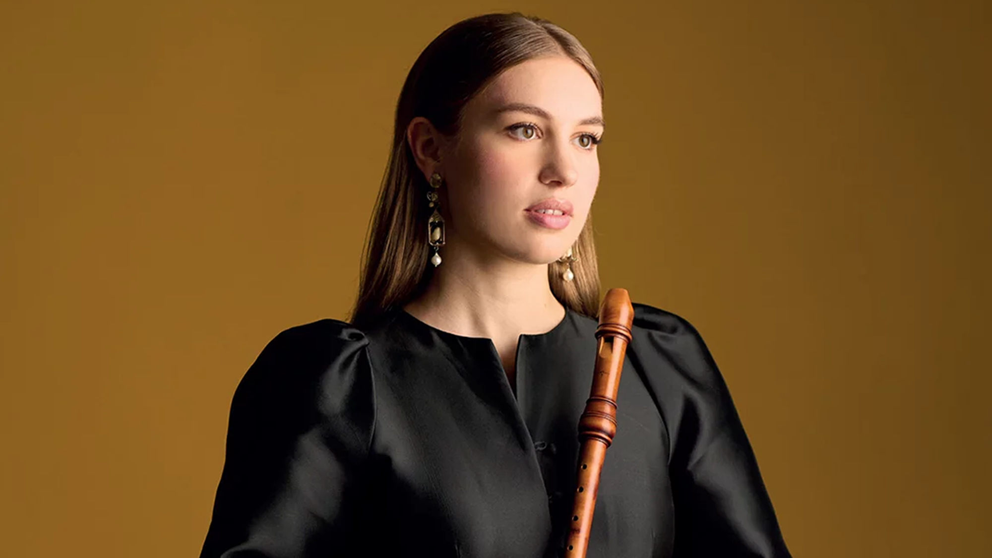 Muzikant Lucie Horsch in een zwarte blouse met een blokfluit in haar hand.