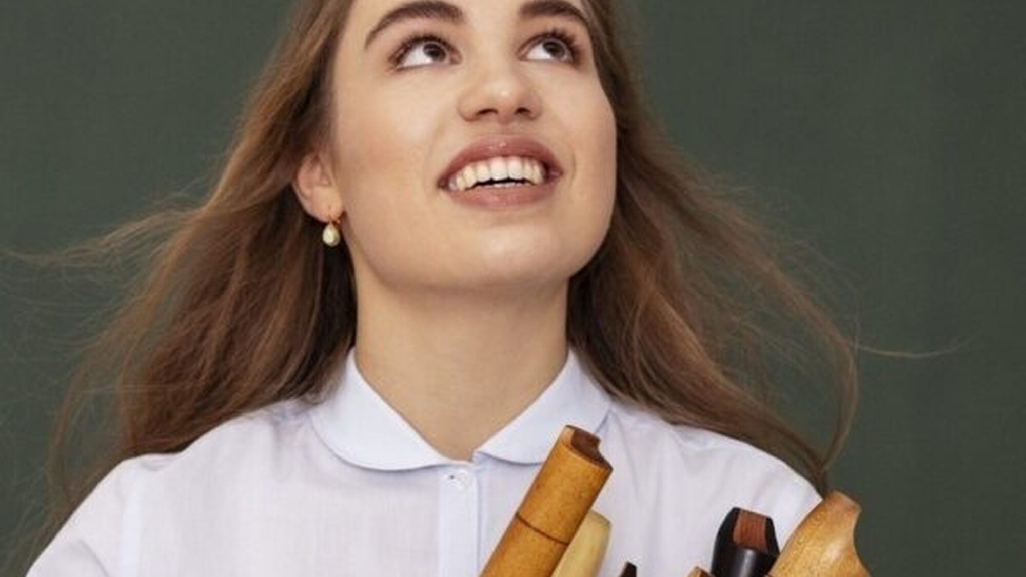 Muzikant Lucie Horsch kijkt omhoog met een aantal blokfluiten onder haar arm geklemd.