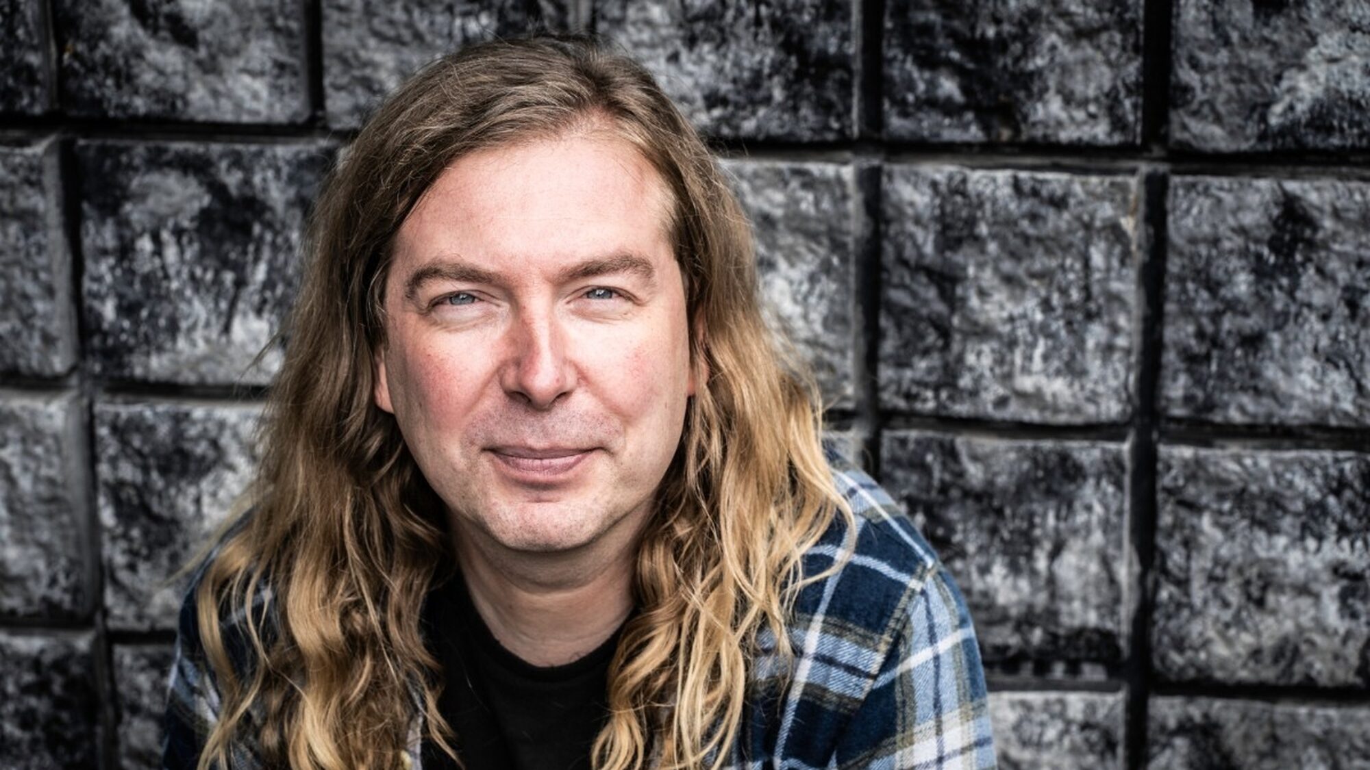 Luuk Bouwman kijkt de camera in met zwarte tegels op de achtergrond