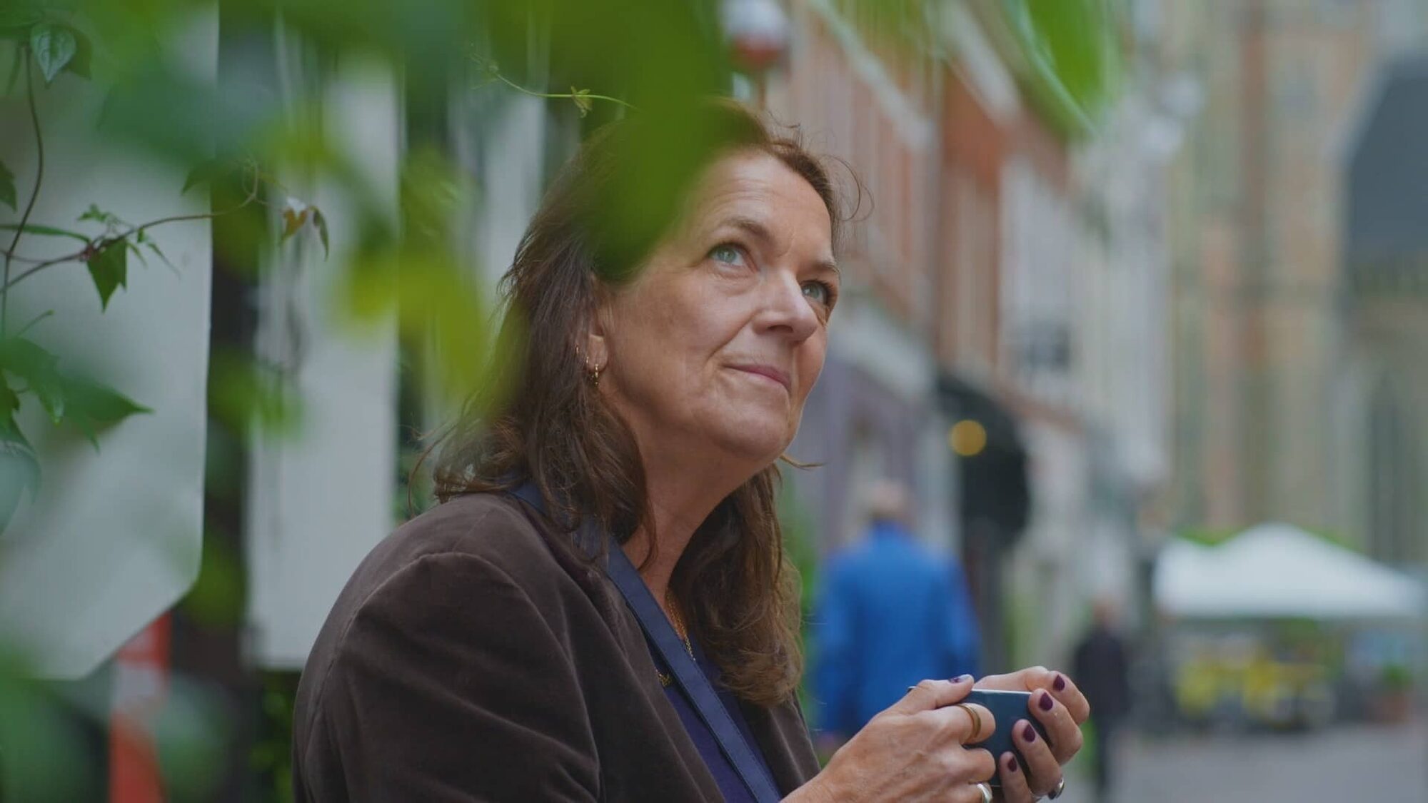 Witte vrouw met bruin haar en blauwe ogen kijkt in gedachte naar boven.