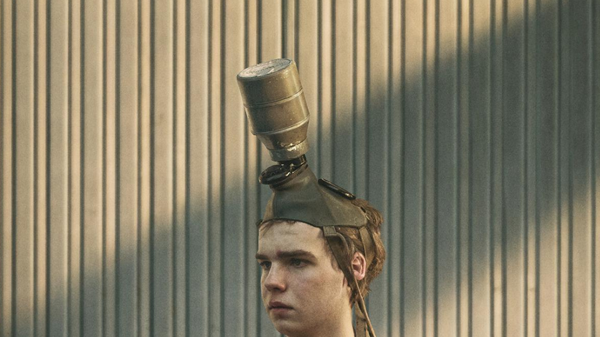 Jongen met schort om en een gasmasker op kijkt naar iets buiten beeld