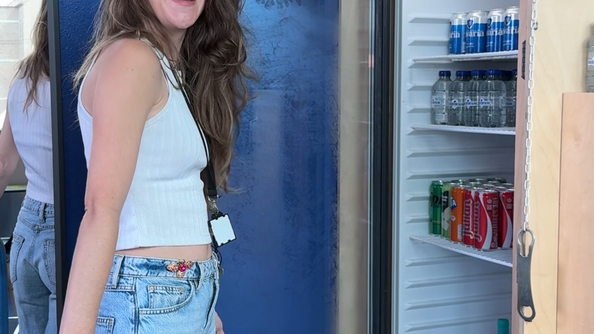 Een foto van Nikki bij een koelkast. Ze kijkt lachend de camera in.