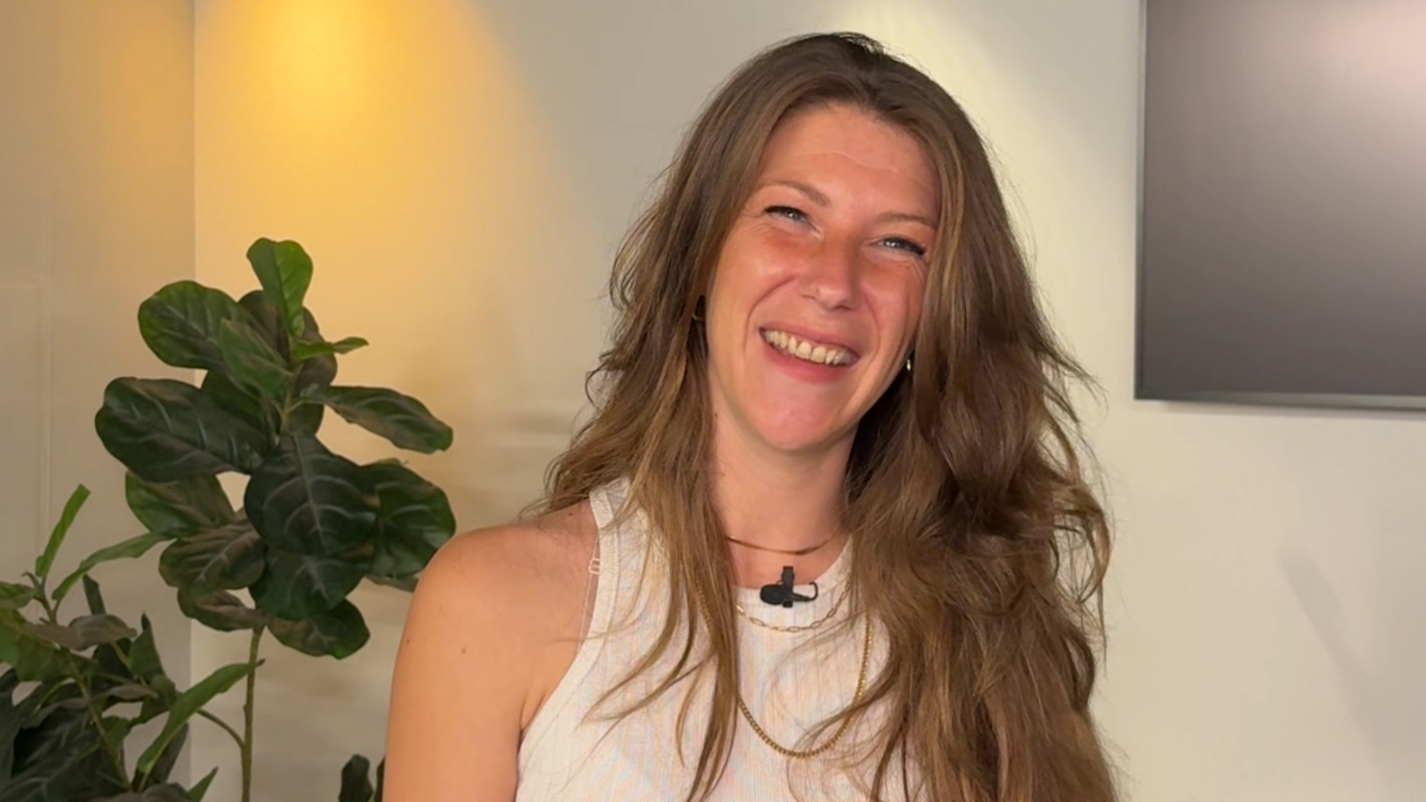 Foto van Nikki, waar dit artikel over gaat. Ze kijkt lachend de camera in. Zee heeft lang haar wat ze los draagt.