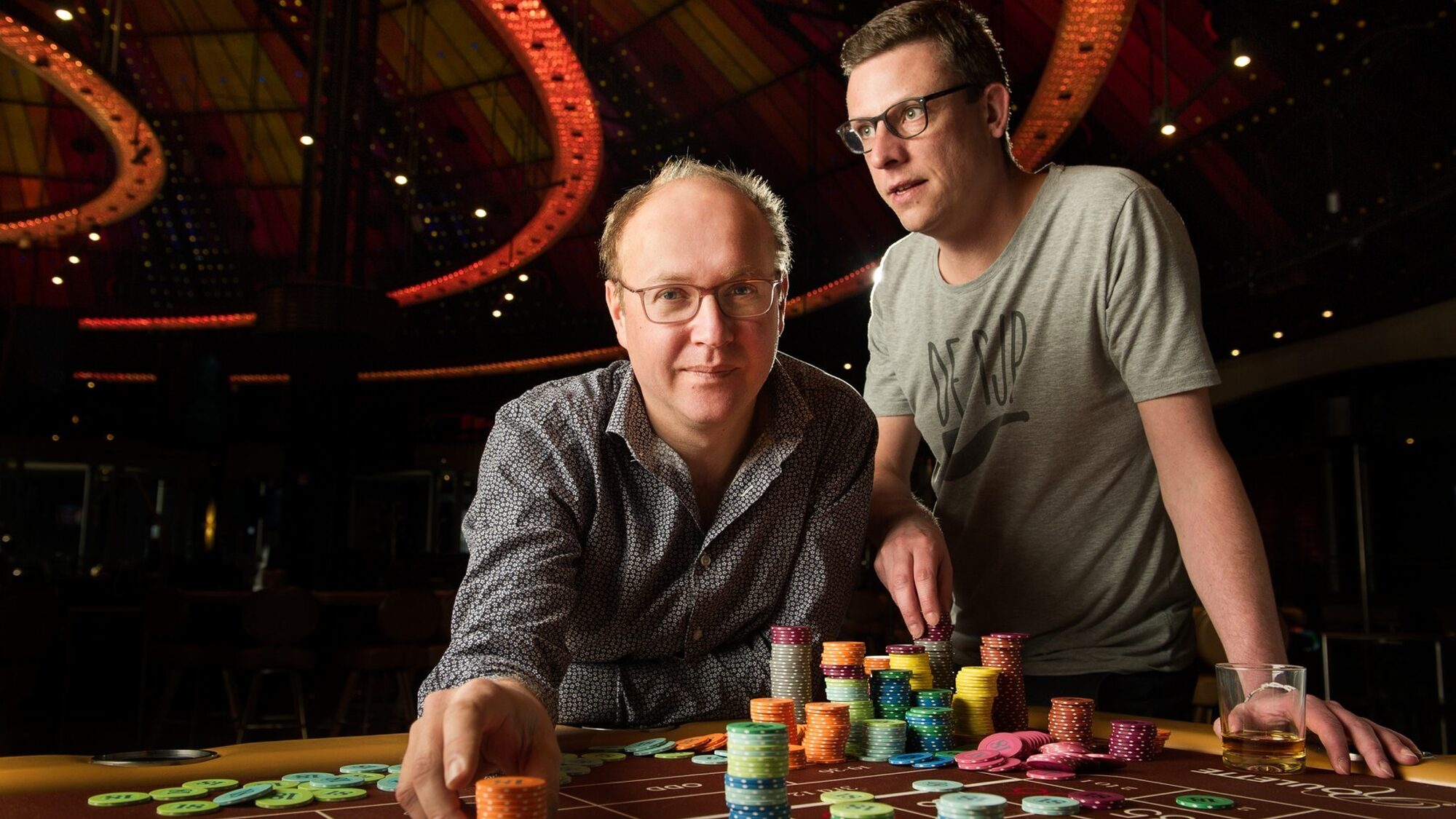 Twee mannen zit rond een tafel vol pokertokens