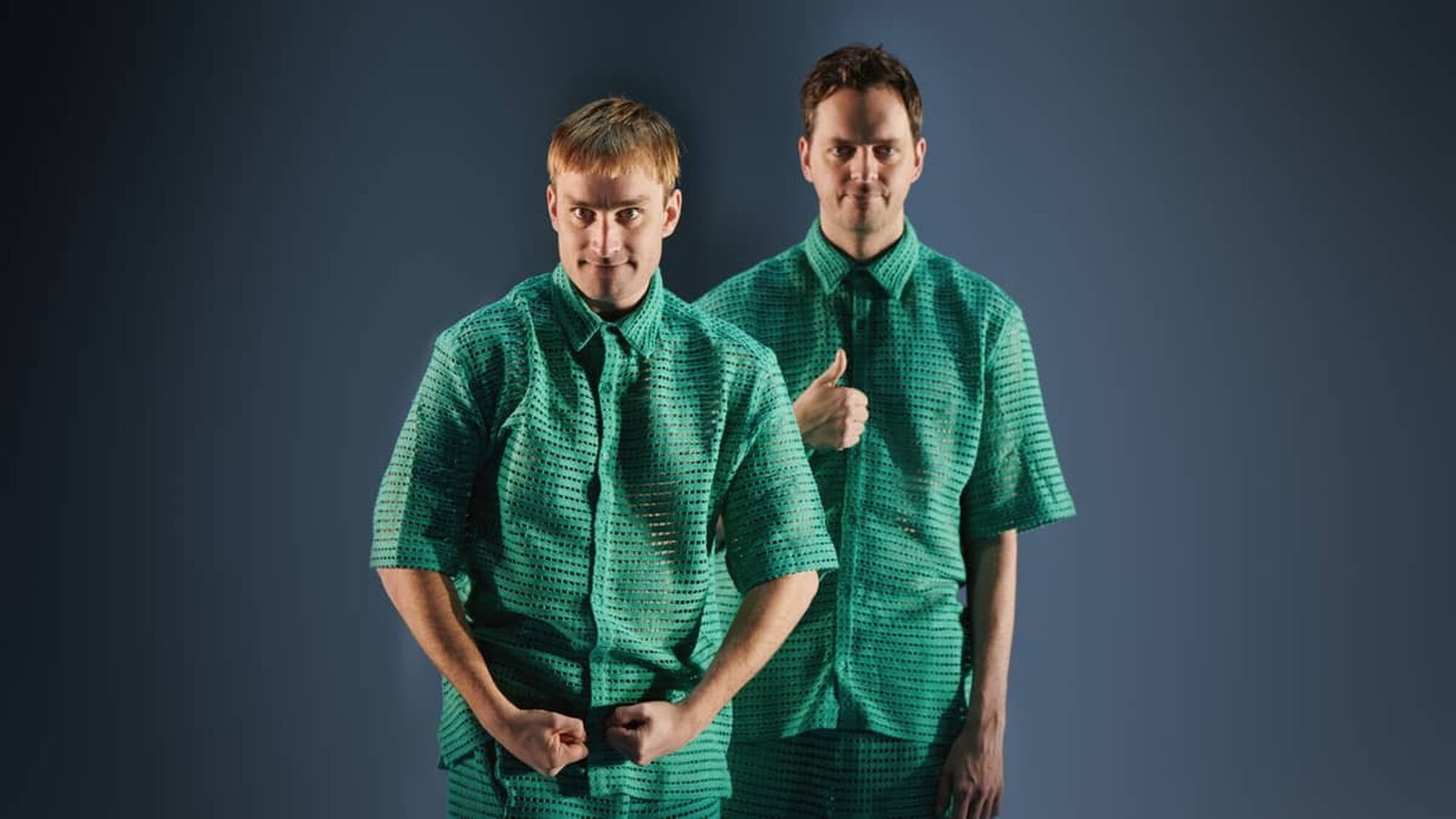 Twee witte jongens in een groen pak kijken verdwaald naar de camera tijdens hun theatervoorstelling