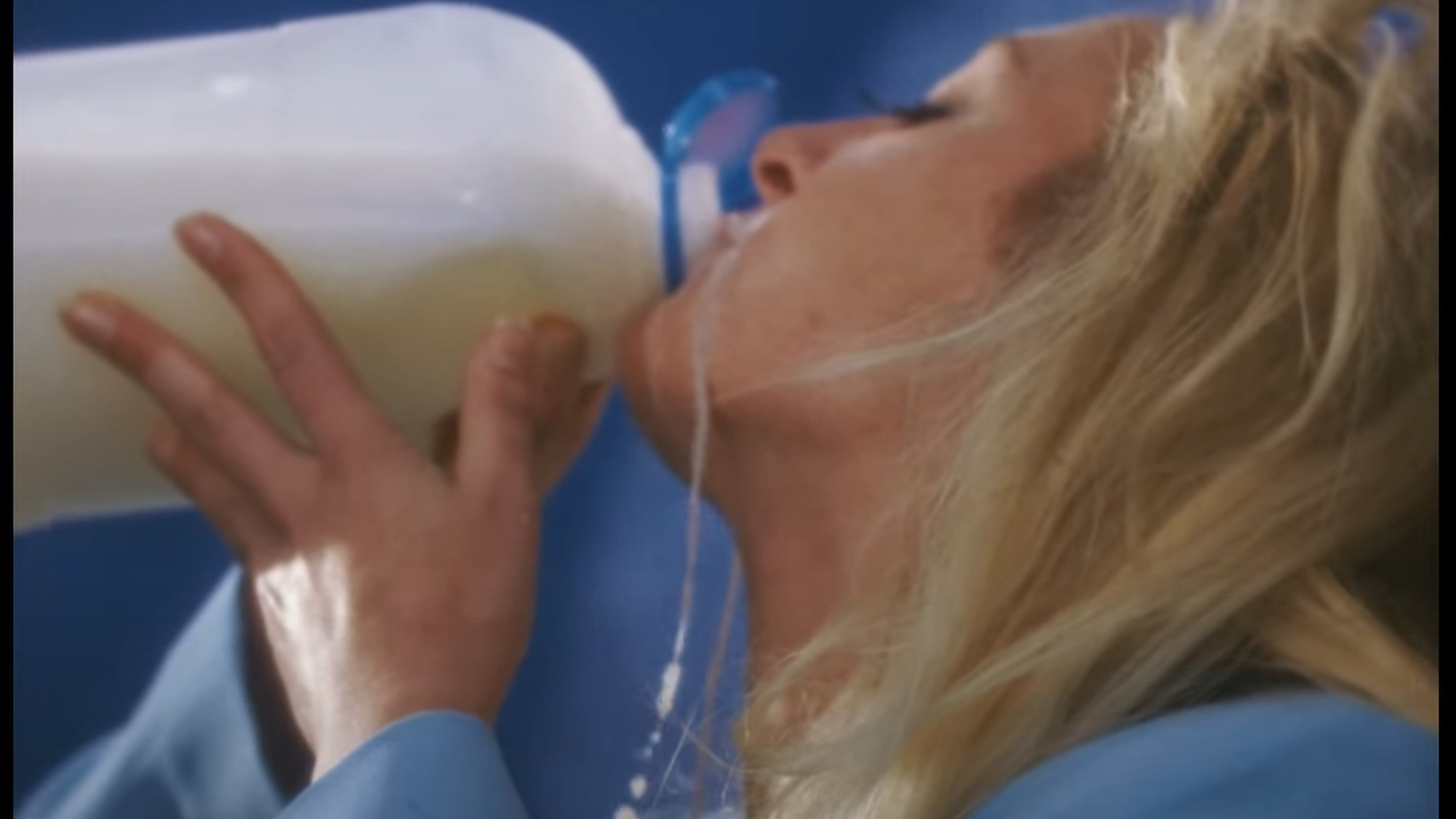 S10 drinkt hier van een pak melk en er druipt melk langs haar nek. Ze heeft een blauwe jas aan.