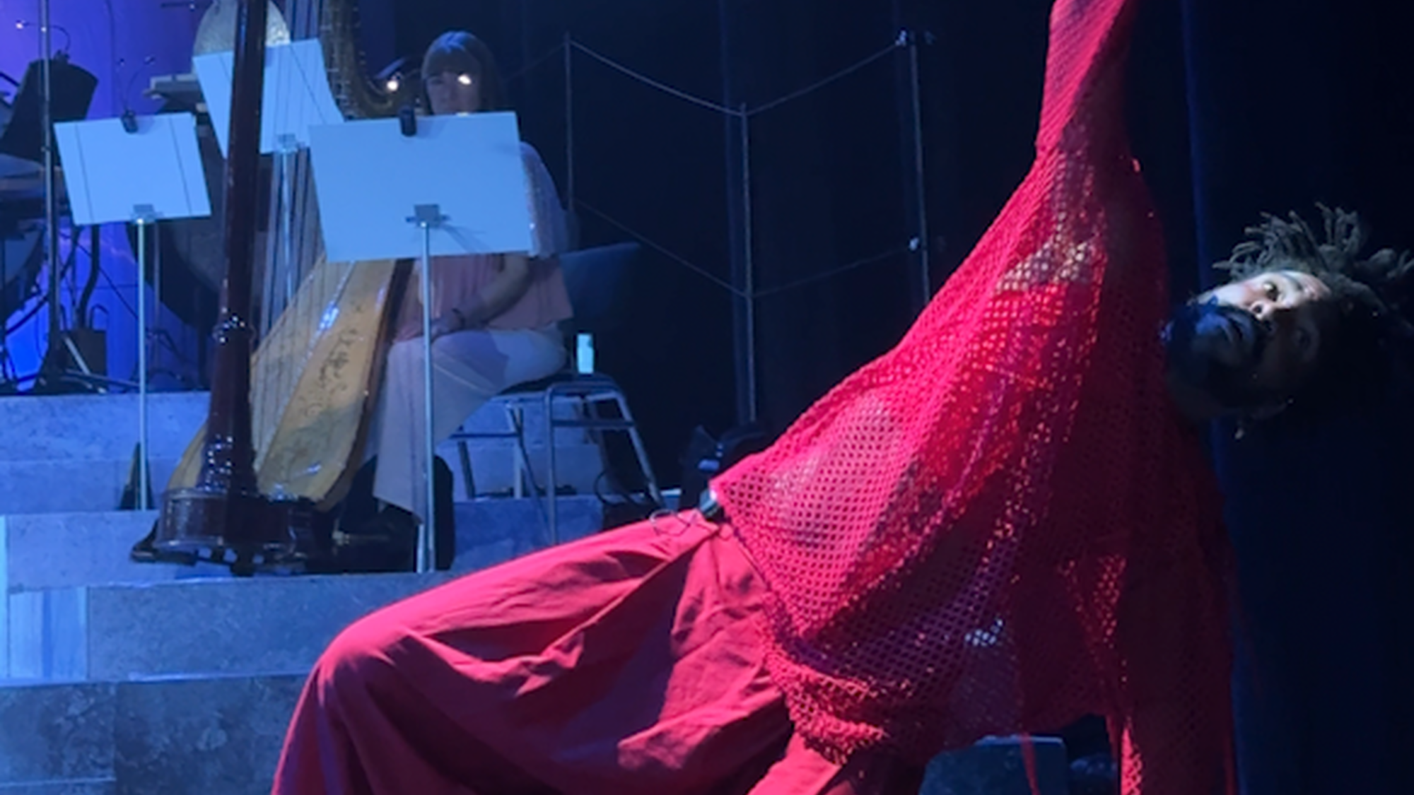 je ziet 1 acteur van kleur met de grijze ijzeren hamer van Thor, de Noorse god. hij vertolkt de rol van Loki in oranje en rode gewaden.