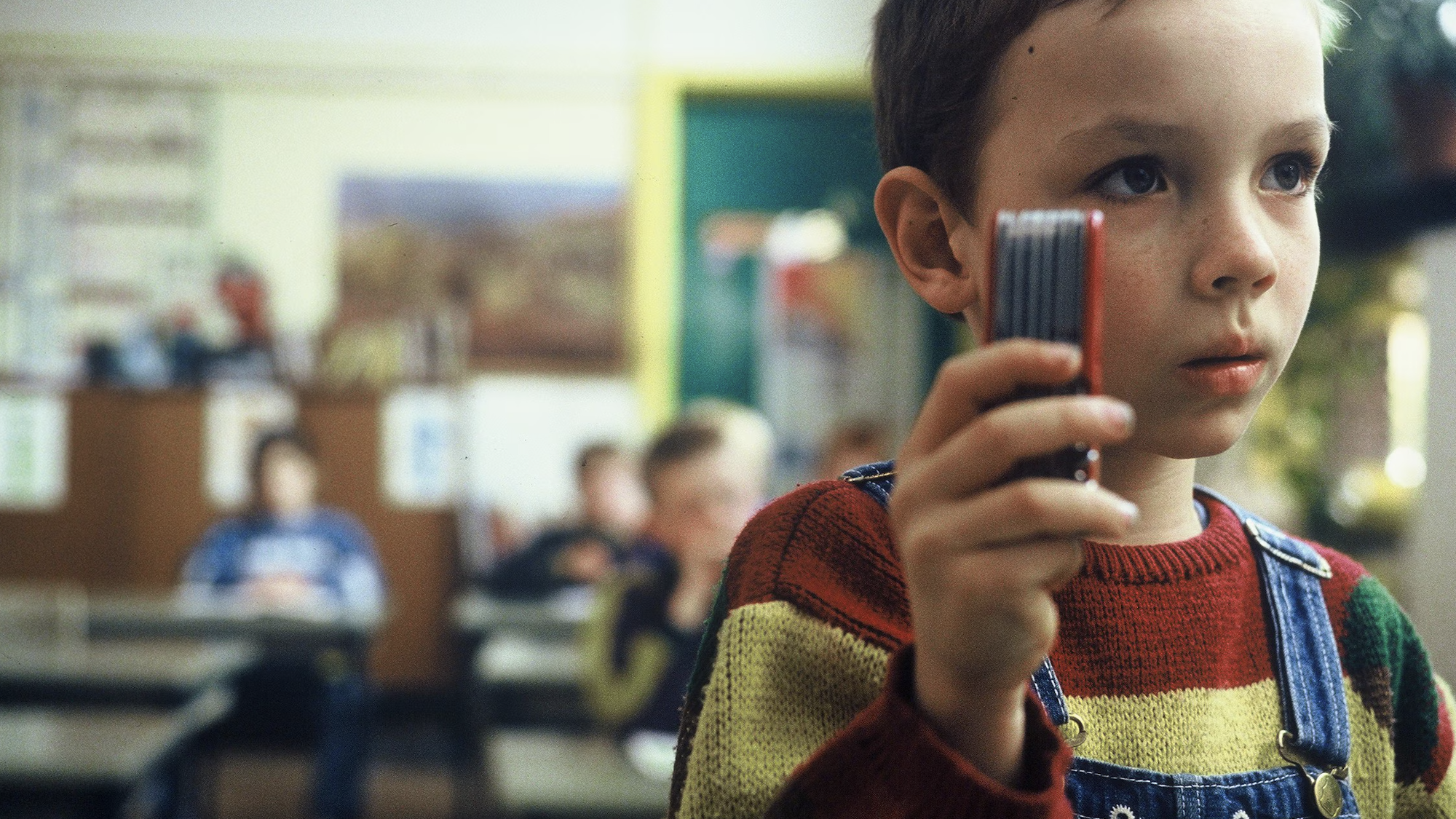 Mees Grobben houdt een zakmes in de lucht in een klaslokaal