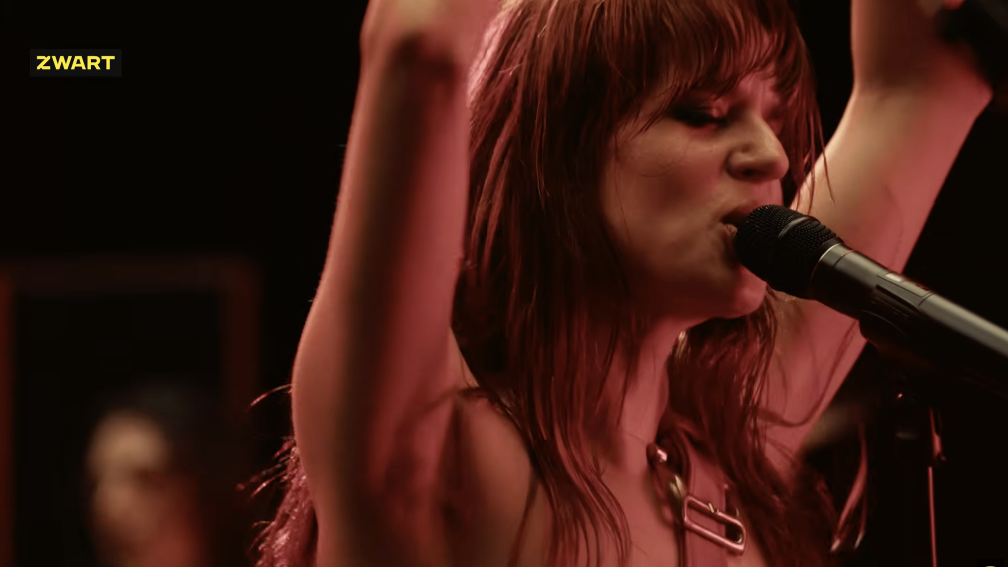 Zangeres MEROL staat in close up met rood licht te zingen