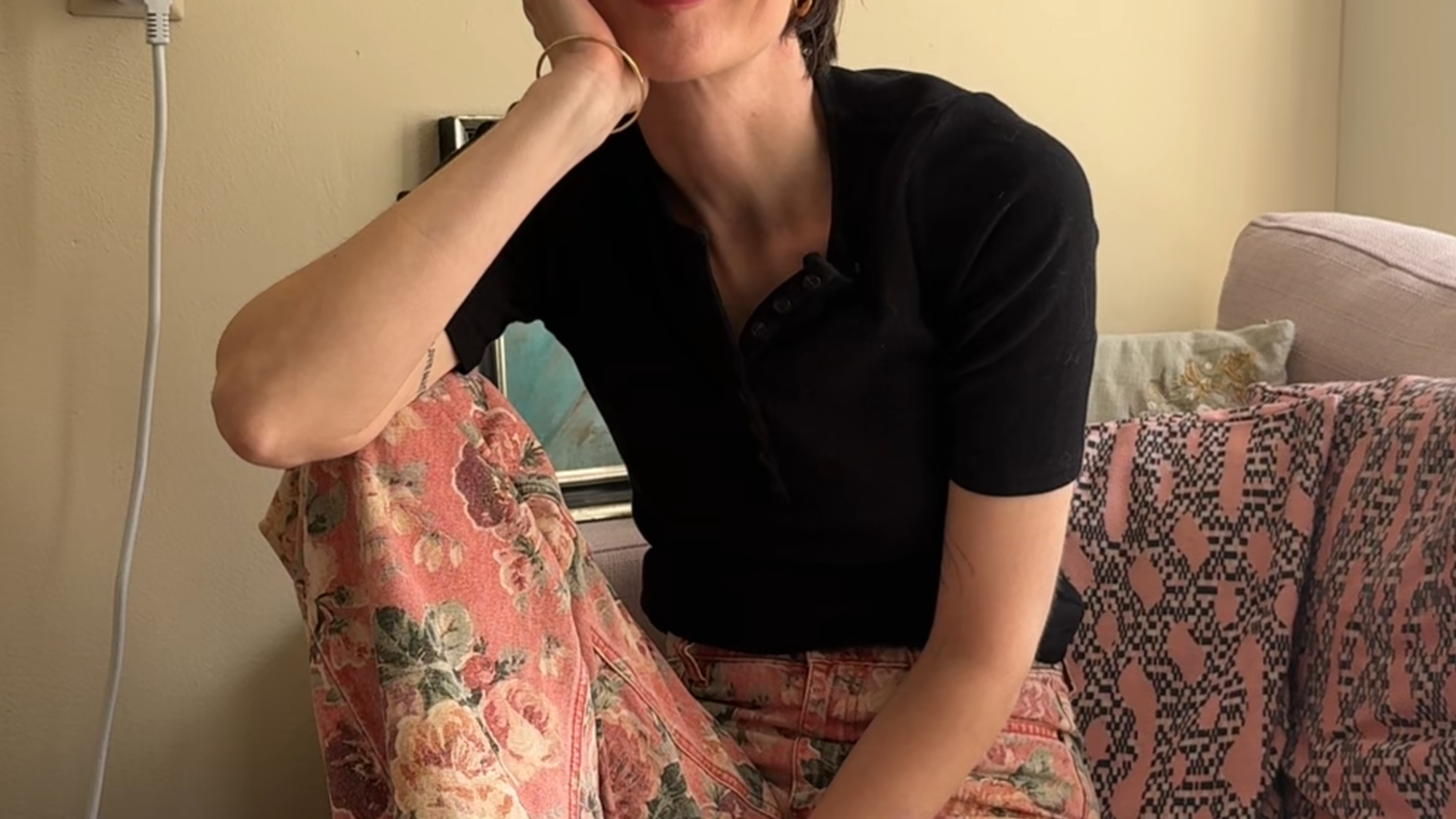 De schrijfster waar dit interview mee is, Sophie Visser, zit op de bank. Ze heeft haar benen opgetrokken en kijkt lachend de camera in.