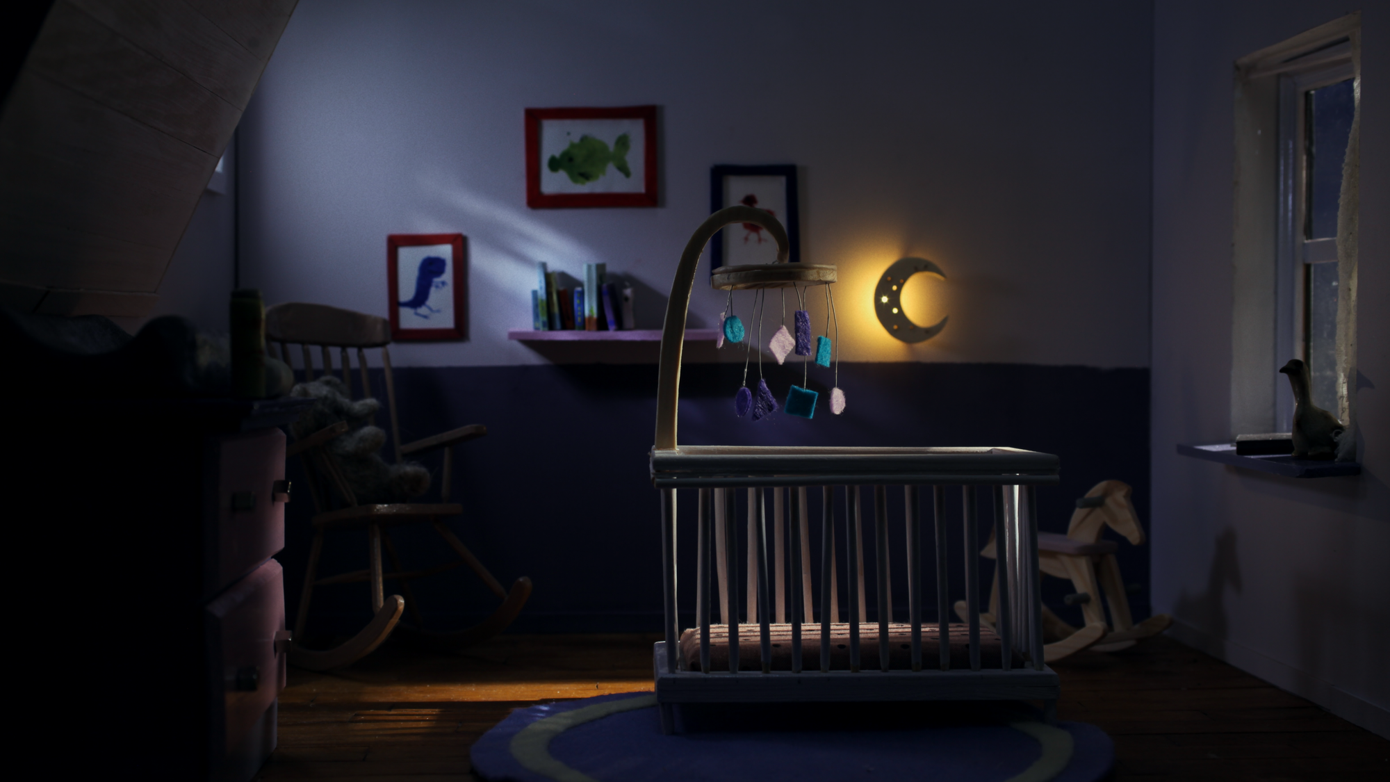 Een stop-motion beeld van een kinderkamer. Er staat een wiegje met een mobiel erboven en er brand een maanvormig lampje in de donkere kinderkamer.