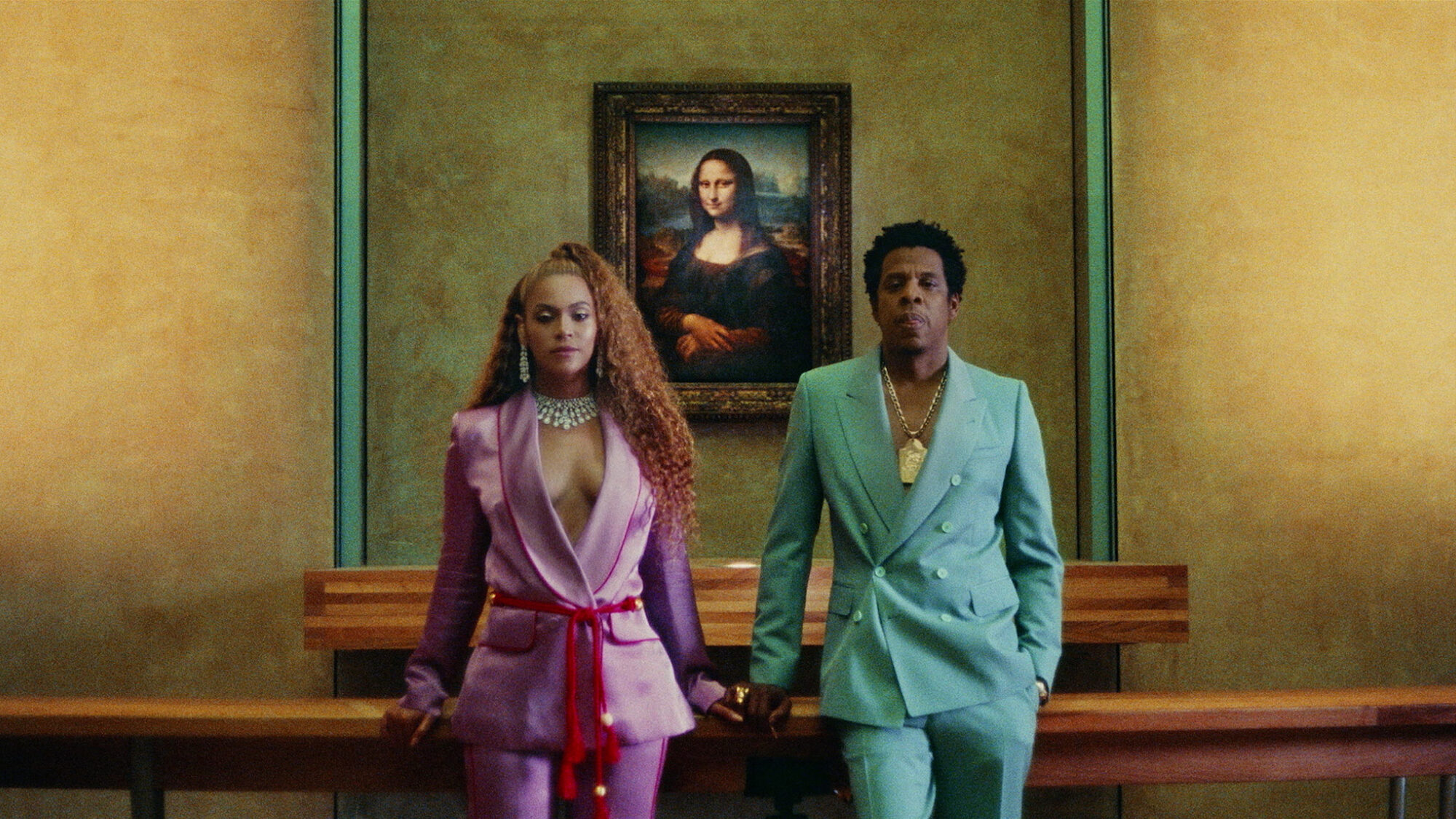 Artiesten en koppel Beyoncé en Jay Z staan voor het schilderij de Mona Lisa in het Louvre. Ze kijken serieus in de camera en dragen allebei gekleurde pakken: Beyoncé roze en Jay Z blauw. Beide dragen ze een grote ketting om hun nek.