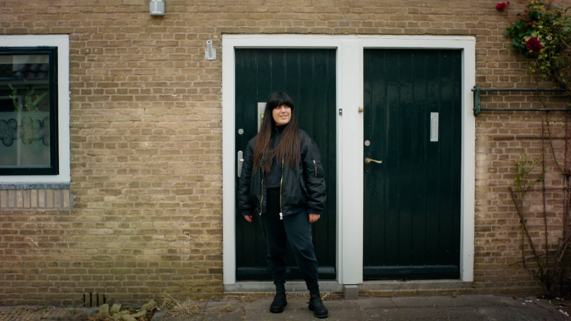 Iraanse vrouw Tina staat blij voor een groene deur van een huis
