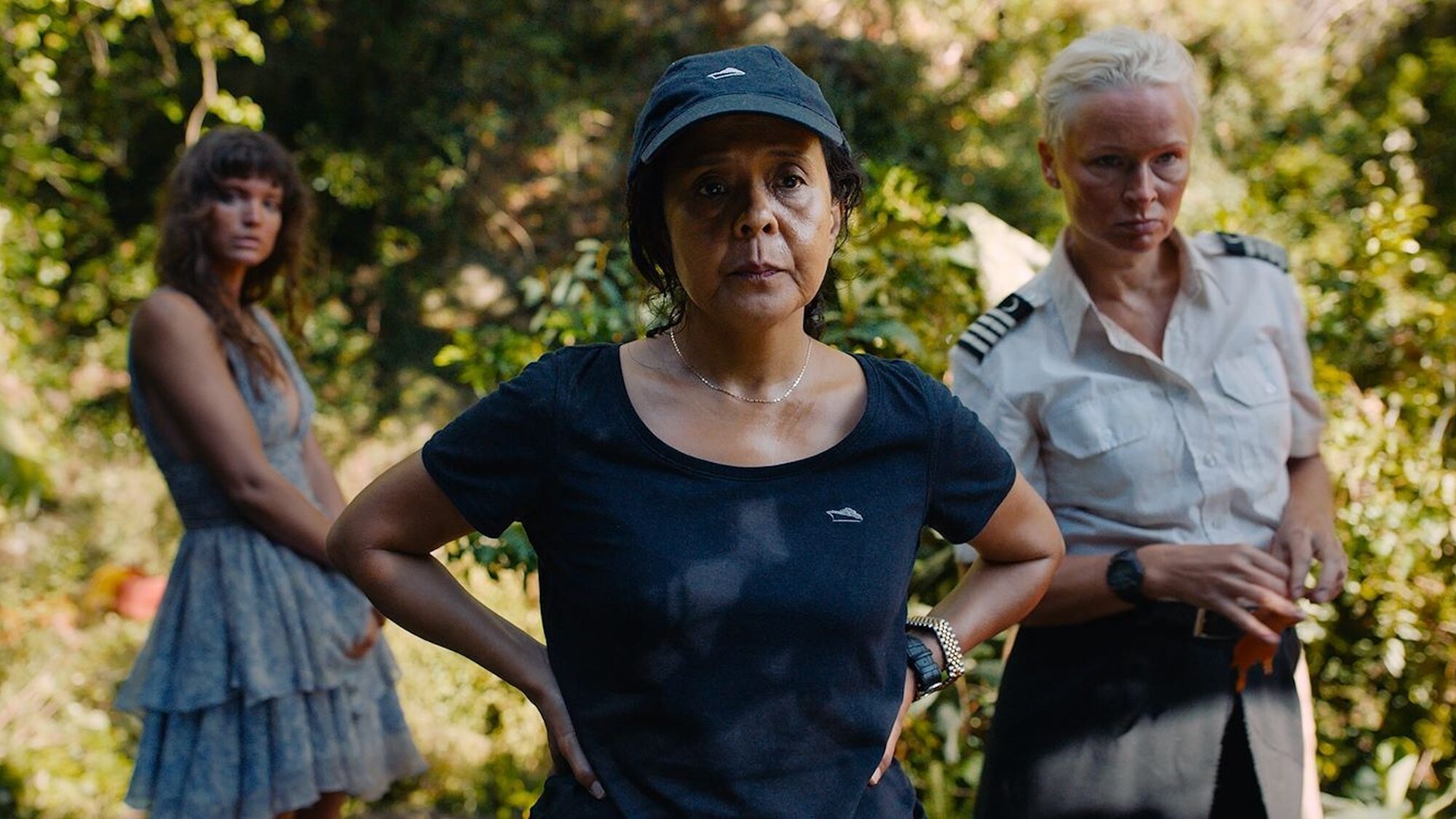 Er staan drie vrouwen op het beeld. De linker vrouw staat op de achtergrond en is niet scherp afgebeeld. Ze heeft een groene bloemetjesprint jurk aan. De middelste vrouw staat met haar handen in haar zij en heeft een zwart T-shirt aan en een zwarte pet op. De rechtervrouw heeft kort geblondeerd haar en heeft een kapiteinkostuum aan.