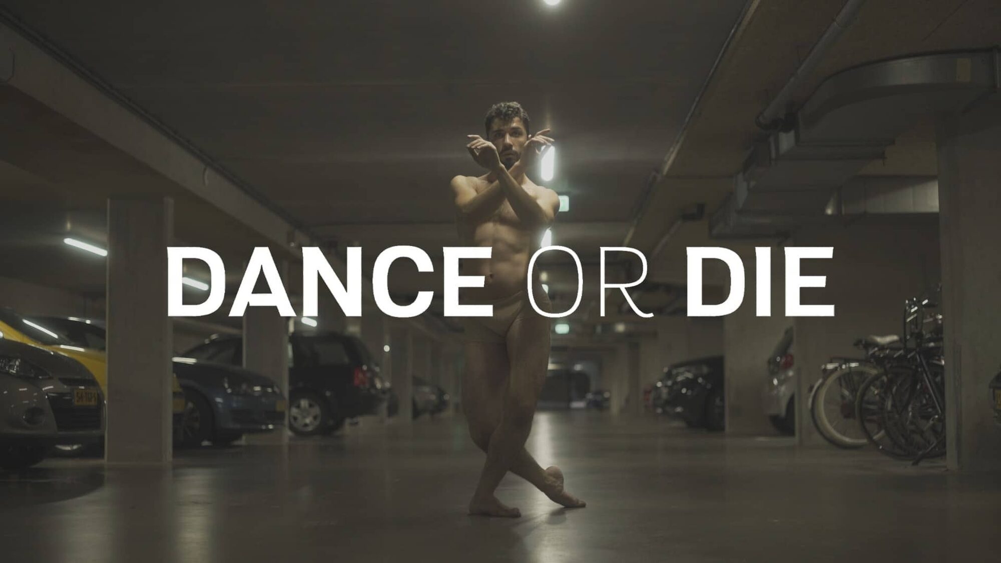 De coverfoto van de documentaire op NPO Start. Je ziet de danser staan met zijn handen gekruist voor zich, in een parkeergarage. In witte letters staat er groot 'dance or die' in het beeld.