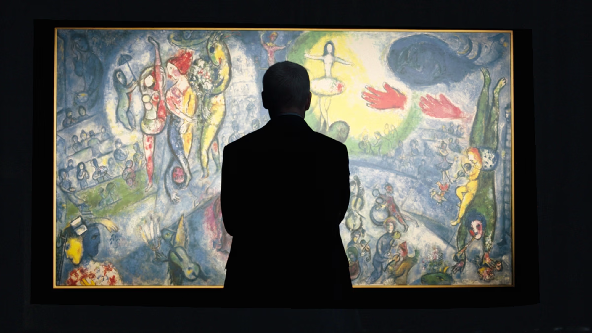 Een stil uit de documentaire. Je ziet een silhouet van een man op zijn rug. Hij kijkt naar een super kleurrijk schilderij, wat helemaal is uitgelicht.
