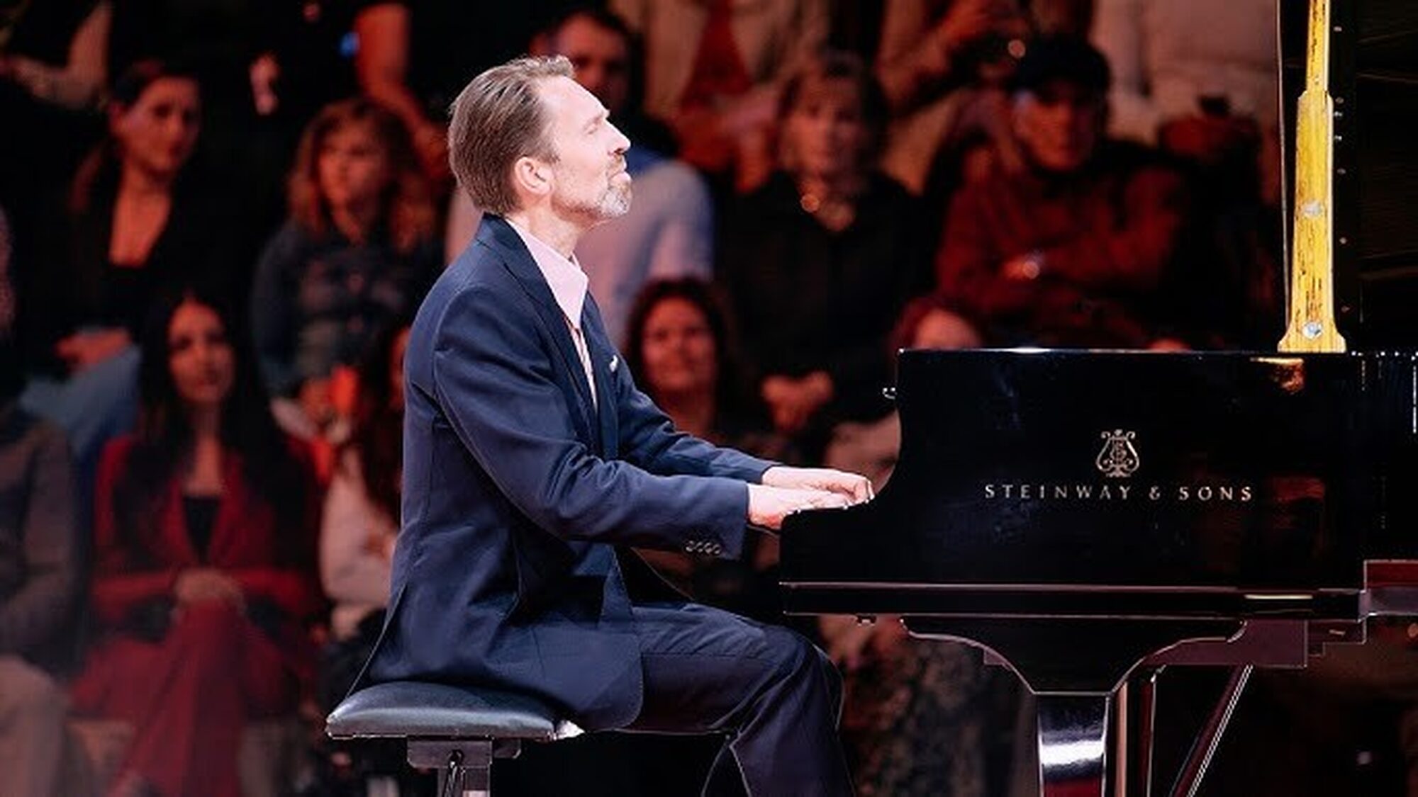 Noorse pianist zit achter een zwarte vleugel op een podium