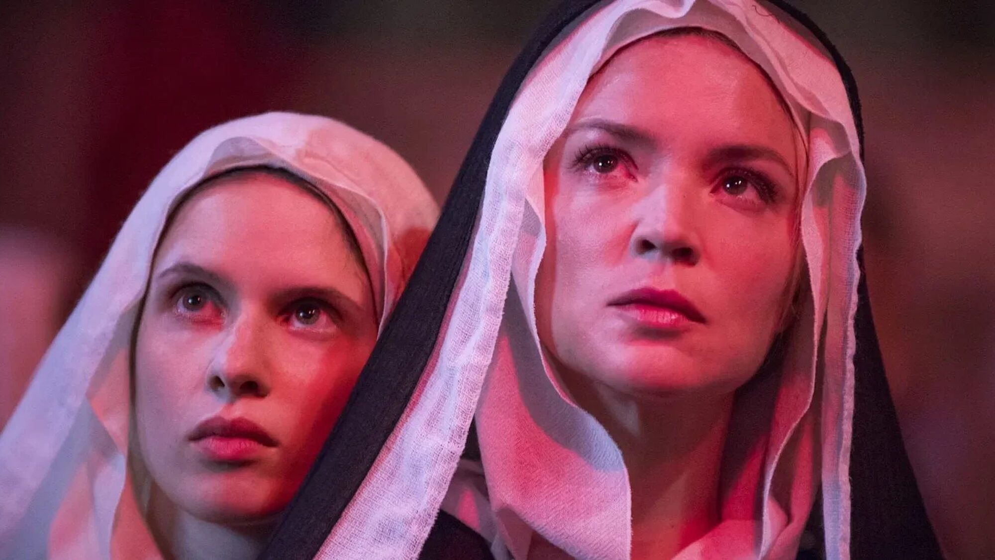 Twee jonge nonnen kijken naar iets buiten beeld