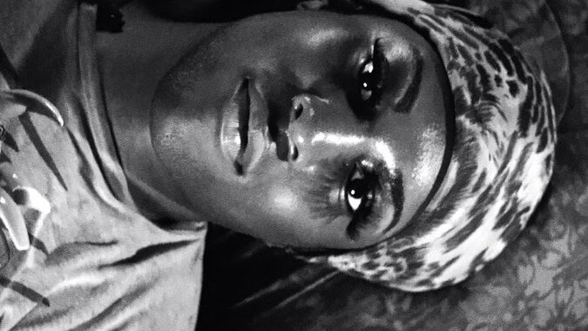 Een van de hoofdpersonen ligt op bed en kijkt verdrietig voor zich uit.