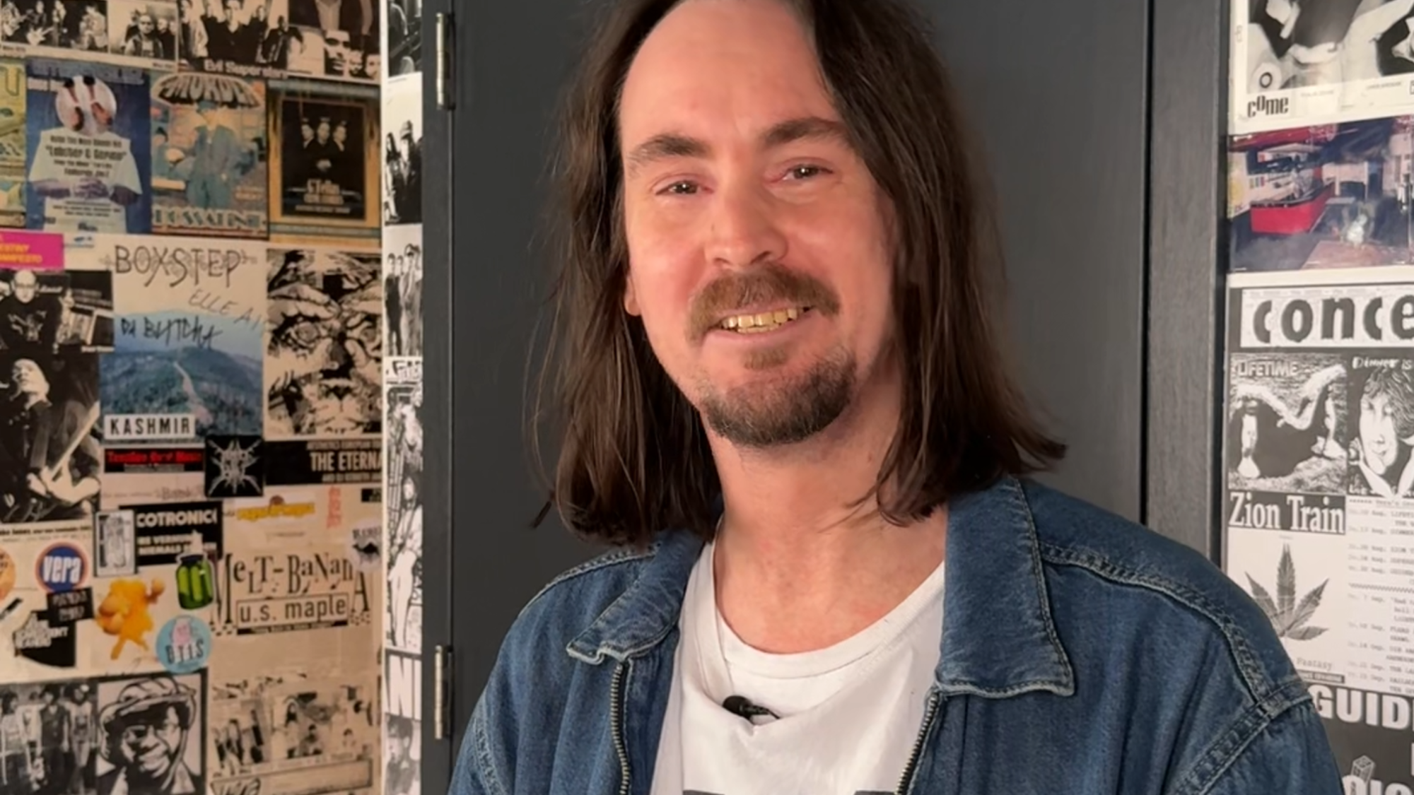 Portretfoto van artiestenbegeleider Mark. Mark kijkt vriendelijk de camera in en staat in een hal.