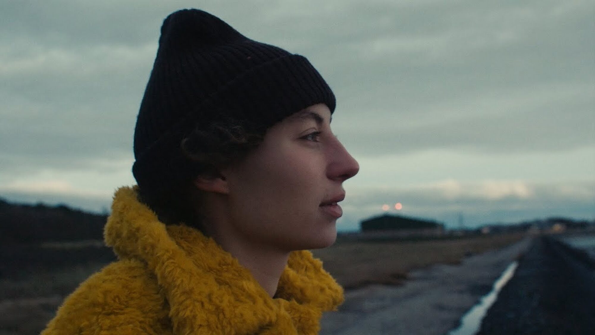 zijportret van Sarah Neutkens. Achter haar is een weg en een bewolkte lucht.