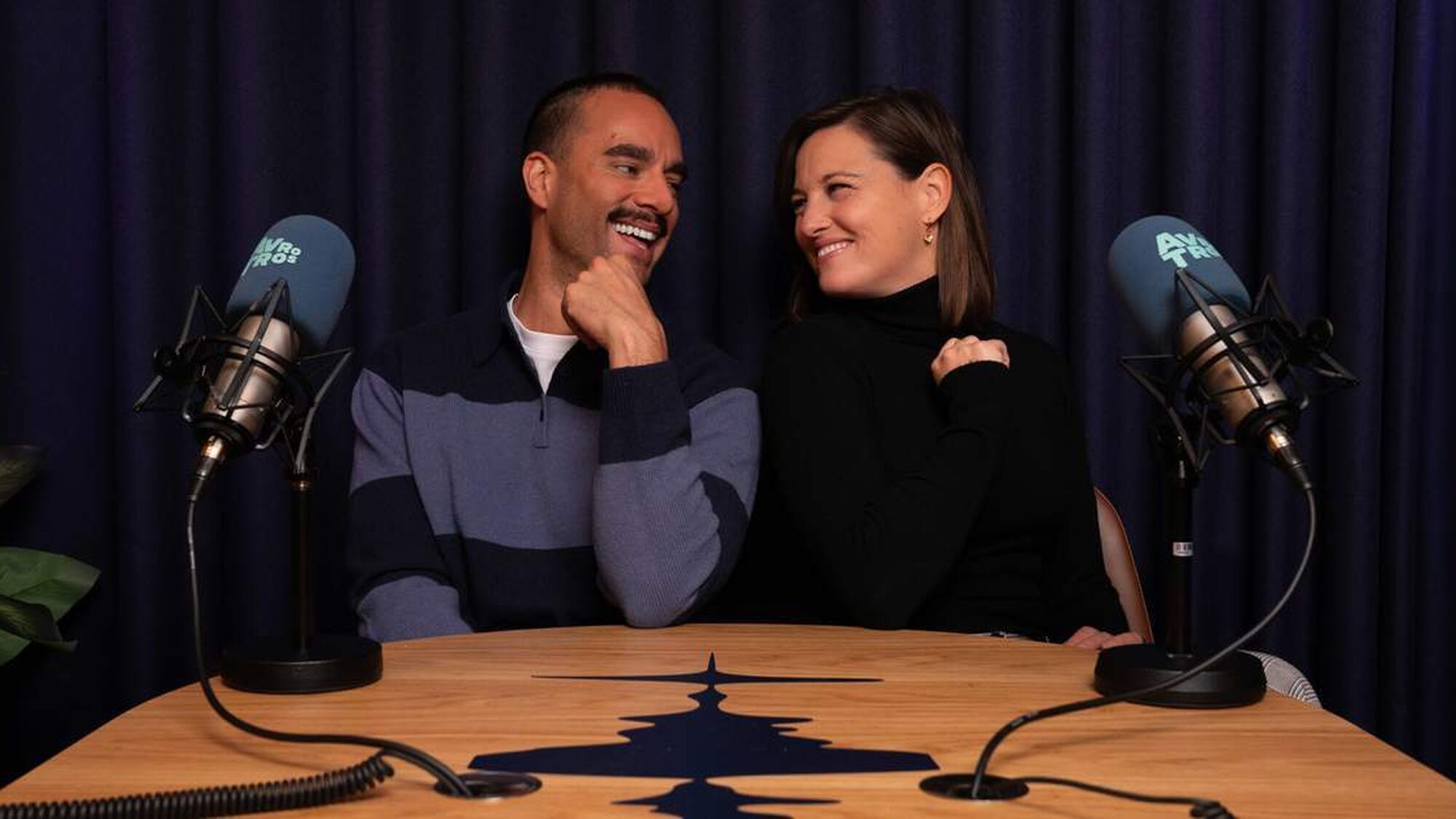 Presentatoren kijken elkaar vrolijk aan in een podcast studio