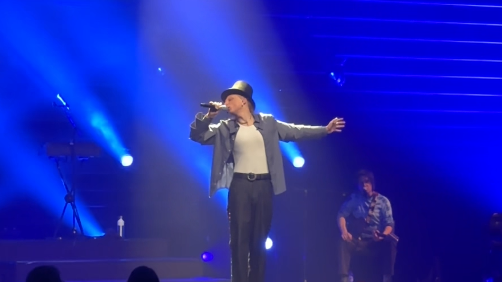 Foto van Scott tijdens de theatershow. Hij staat op een groot podium met podiumlampen en hij heeft een hoge hoed op.