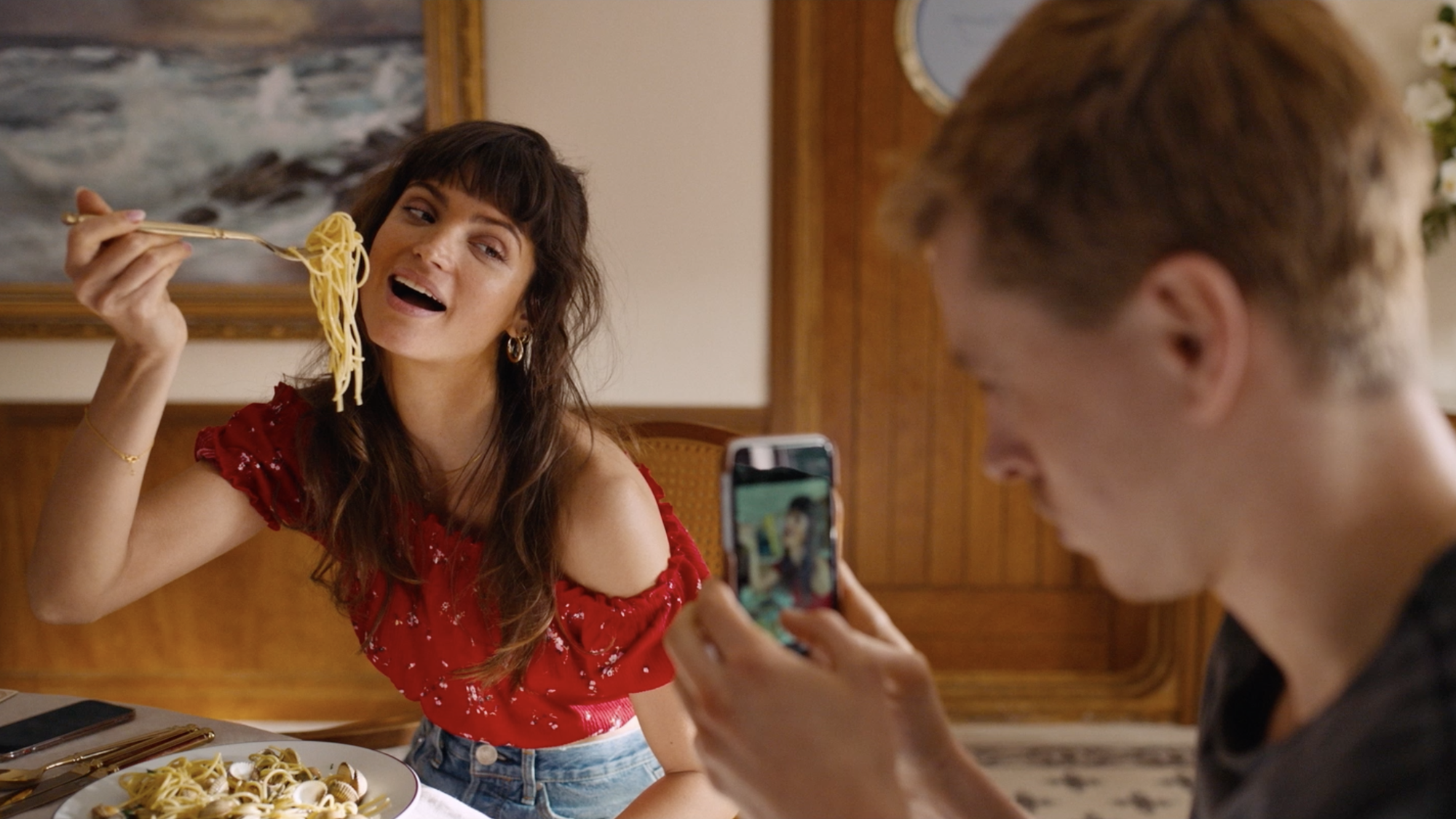 Man fotografeert een vrouw die poseert met een vork spaghetti