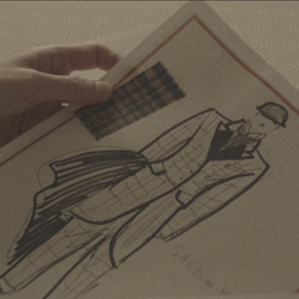 Een hand houdt een modeschets vast.