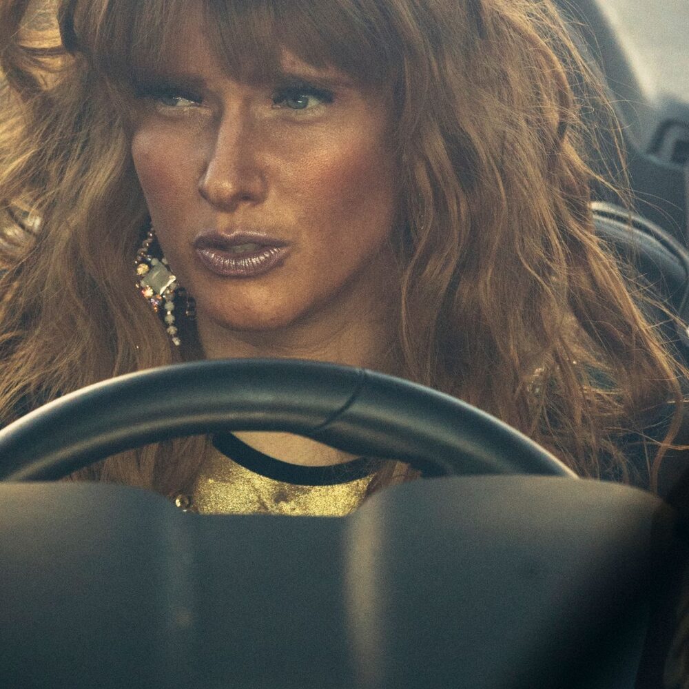 Een prachtige vrouw met gouden make-up zit achter het stuur