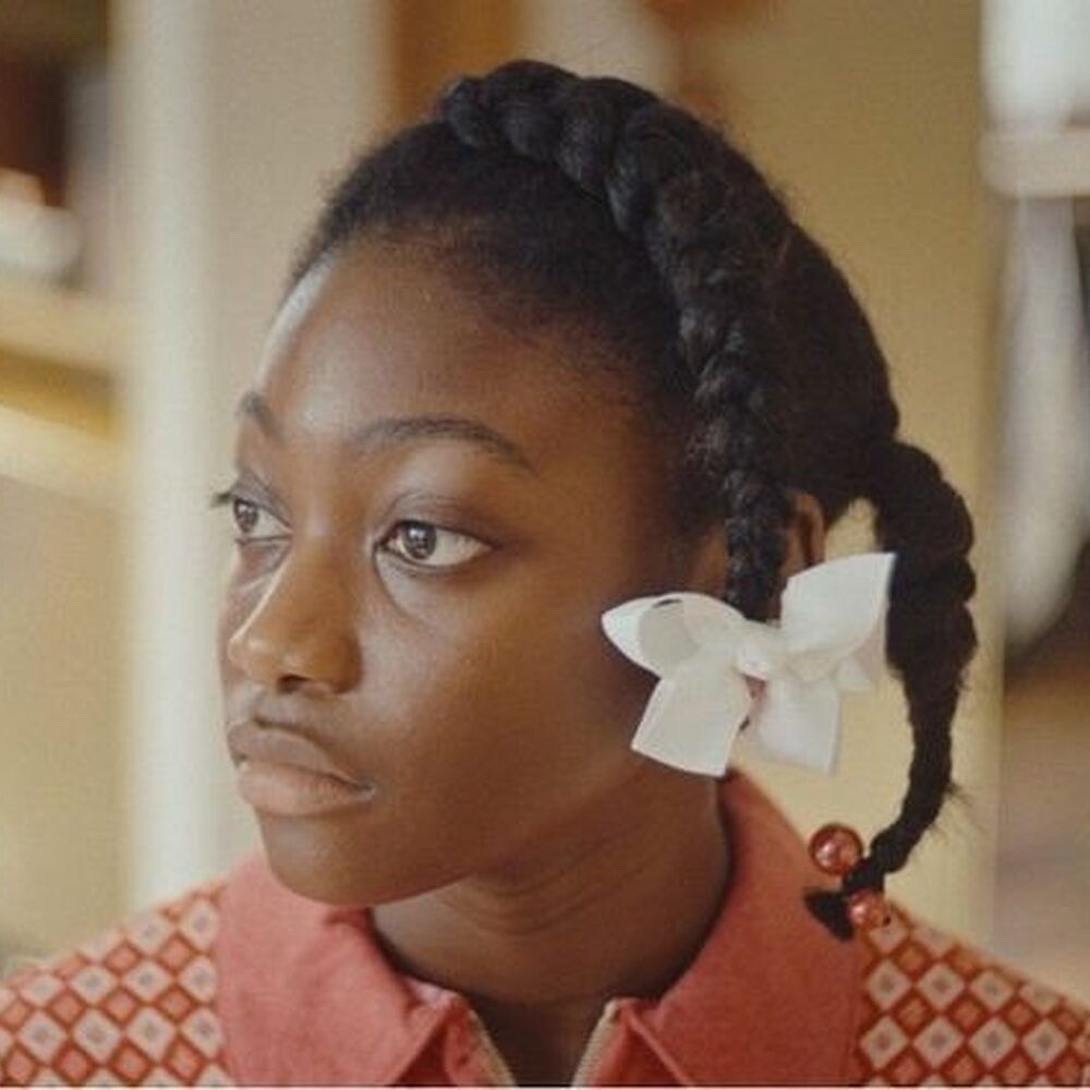 Meisje met witte bloem in haar vlecht kijkt naar iets dat buiten de camera is