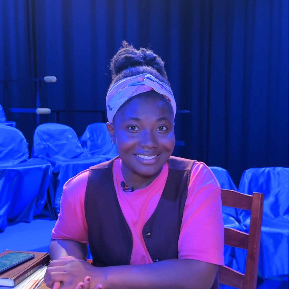 Op deze foto zien we Kimberley. Ze zit aan een tafel en kijkt vriendelijk lachend de camera in.