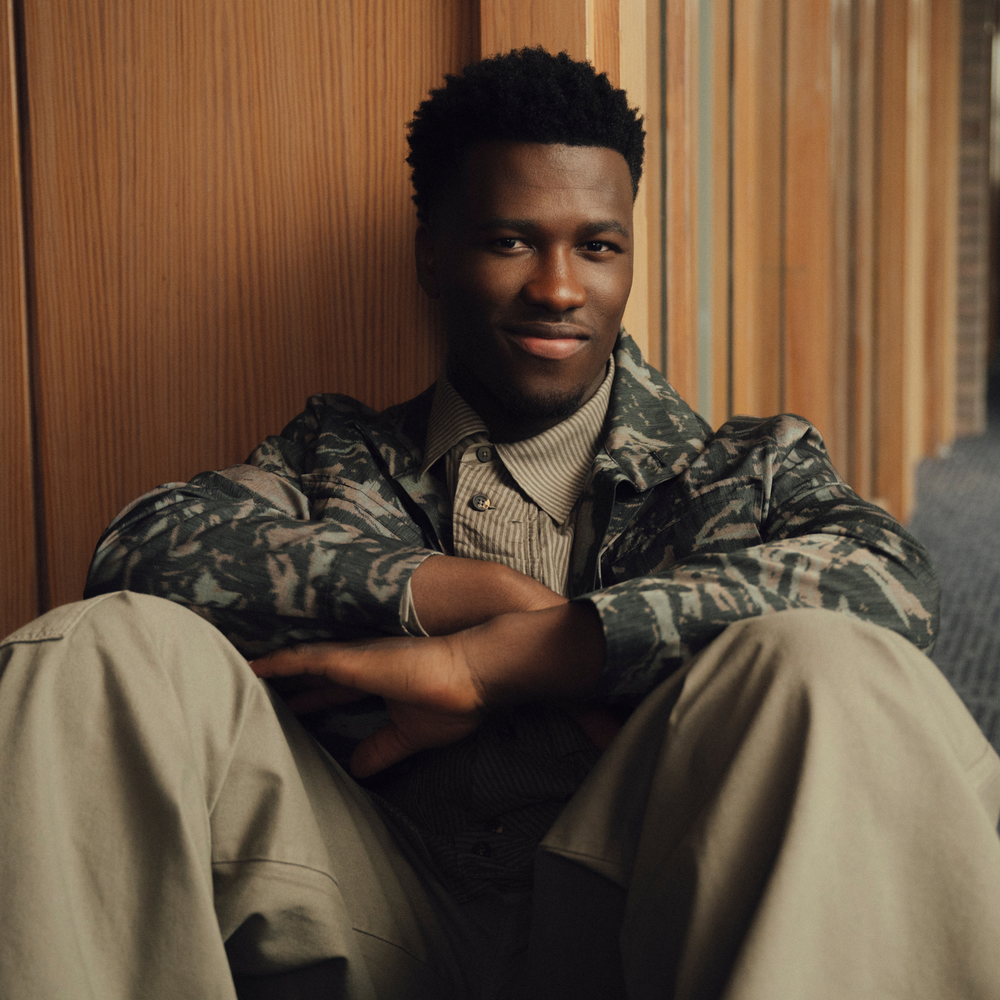 Foto van zanger Claude, die achterover geleund tegen de muur zit