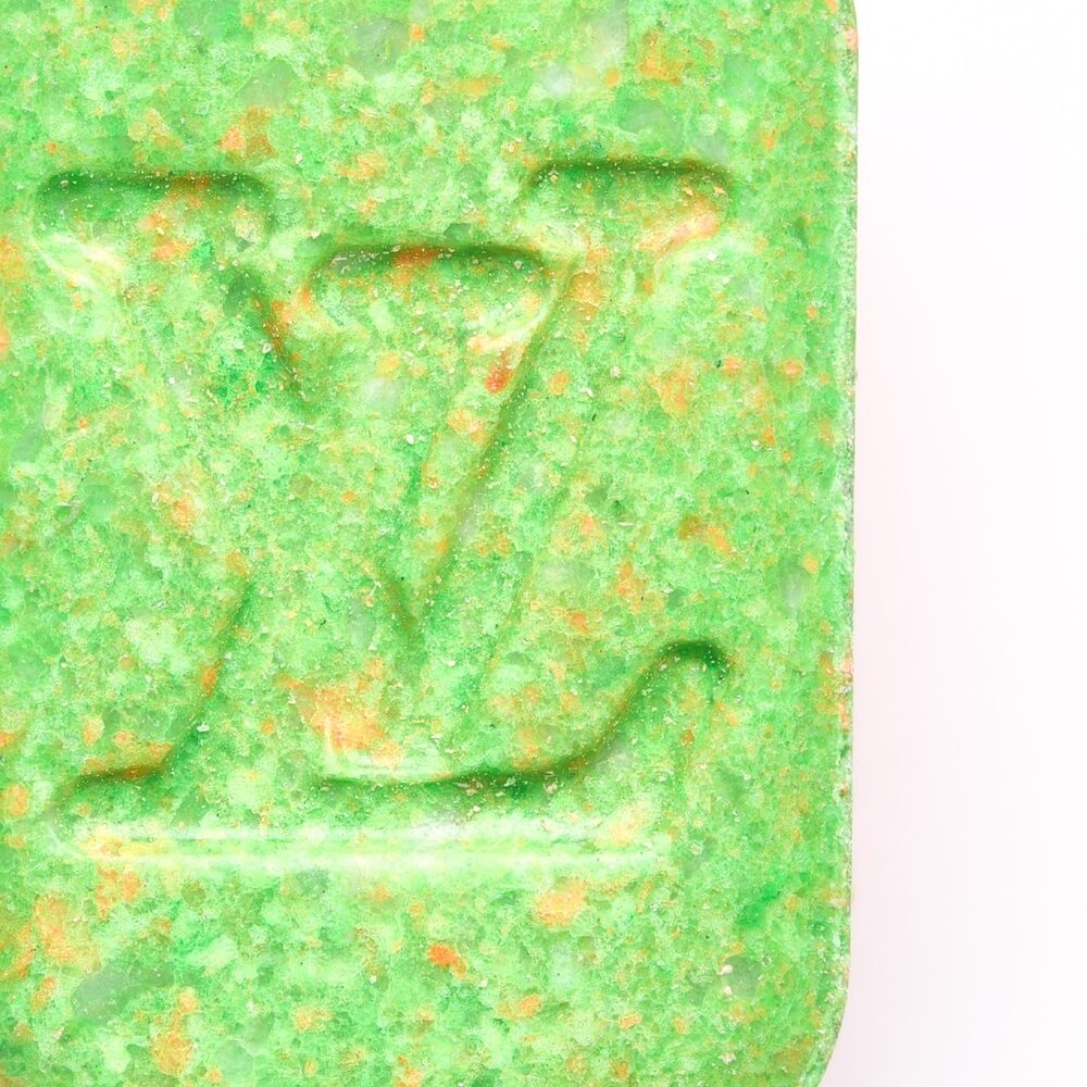 Close up van een groene XTC-pill met het Louis Vuitton logo