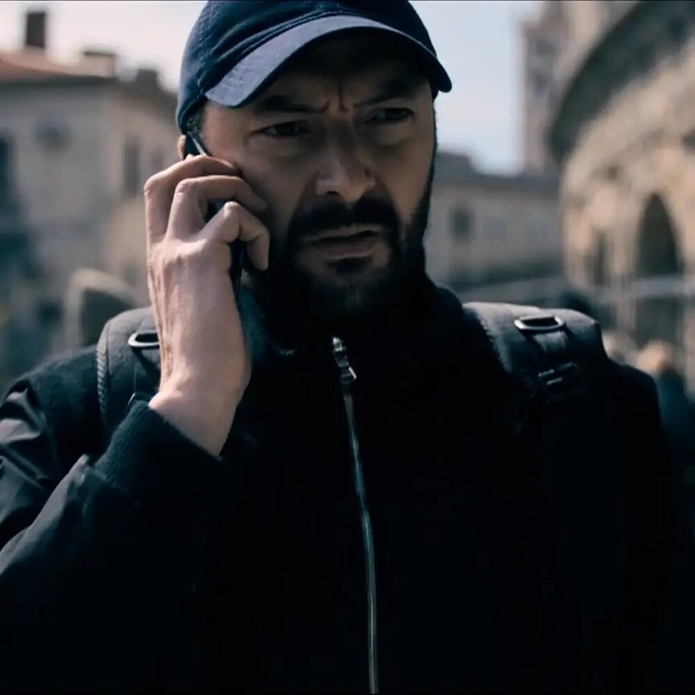 Een man met een pet op belt en kijkt fronsend.