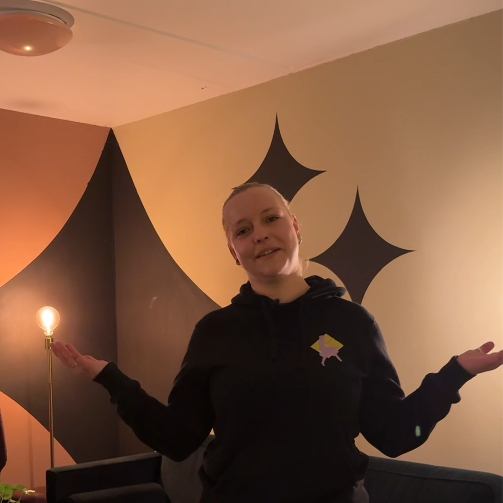 Izanka in de kleedkamer die ze laat zien. Ze houdt haar handen half omhoog naast haar lijf, alsof ze haar schouders ophaalt.