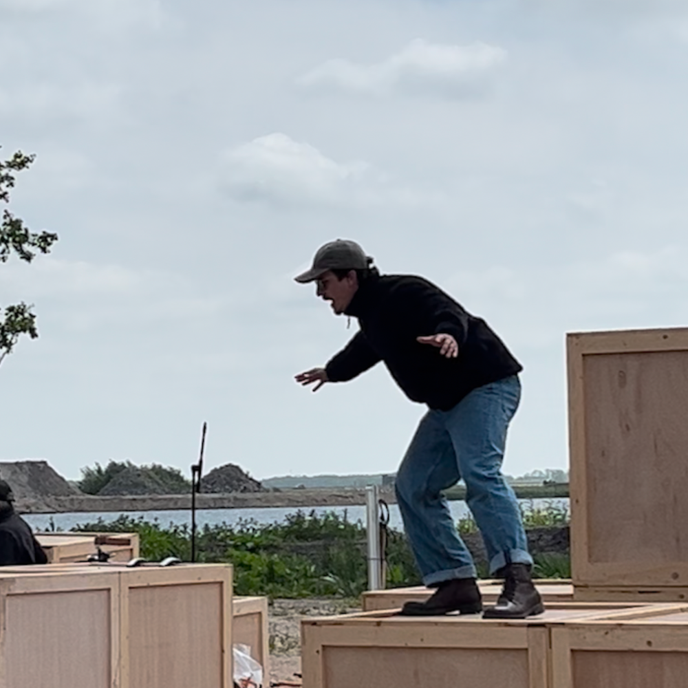 Stil uit een scene van het stuk. Acteur Jurriaan staat op een houtenblok op de zandafgraving in Nij Beets.
