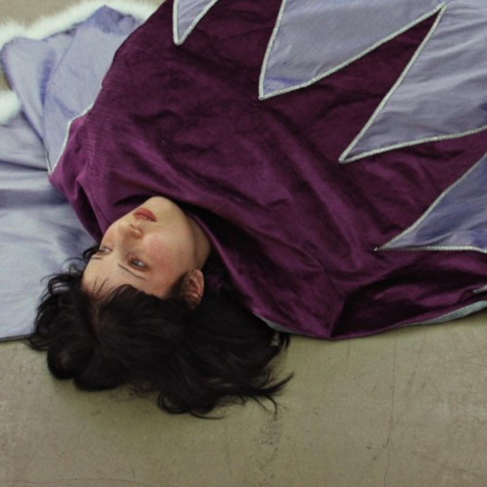 Vrouw ligt op de grond in paars gewaad