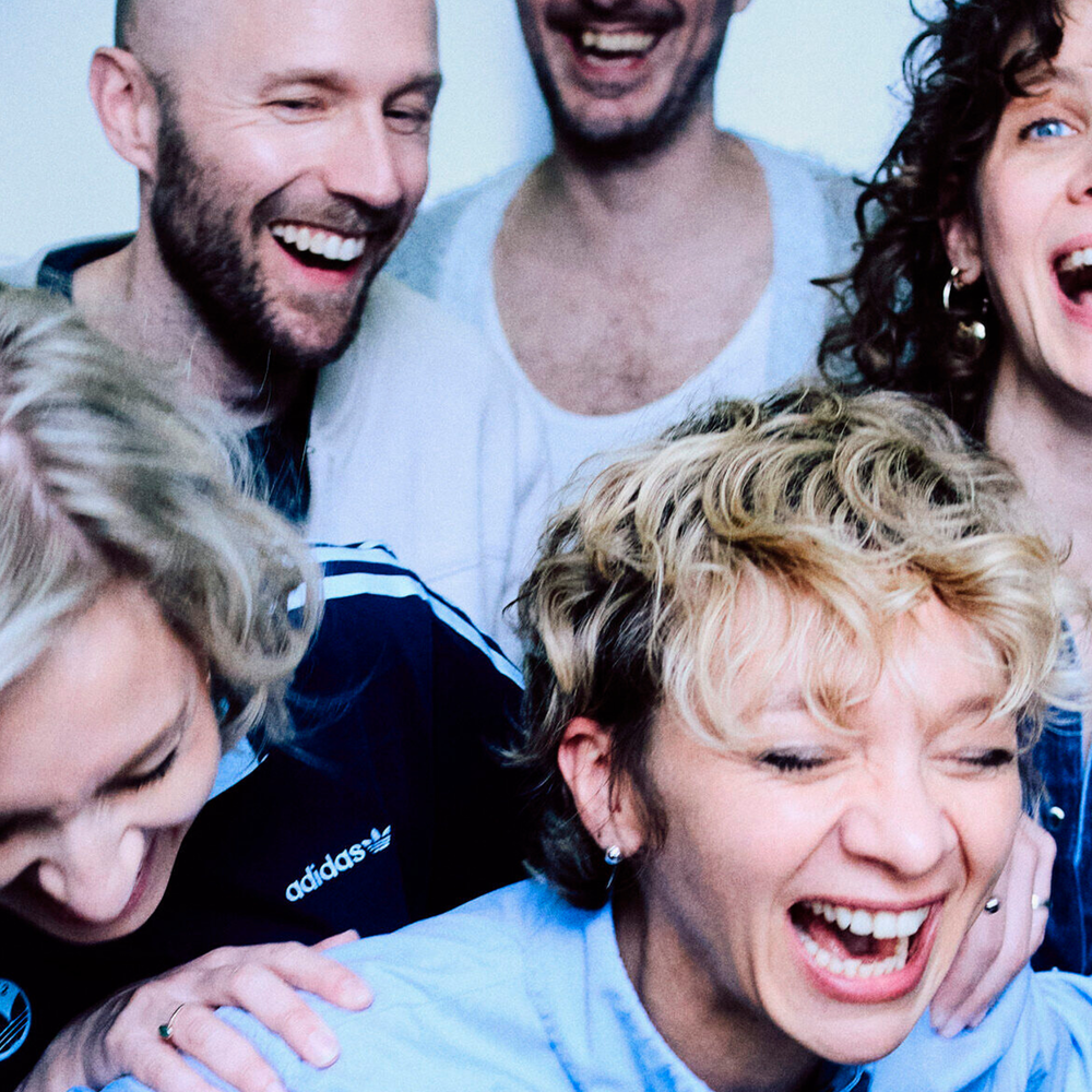 Foto van de band Krezip. Een chaotische foto, van lachende mensen in de lift, van heel dichtbij genomen.