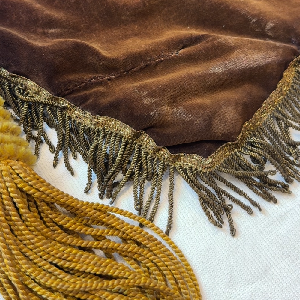 Close-up foto van een scheurtje wat weer dichtgenaaid is in het bruin-fluwele vaandel.