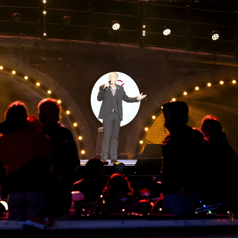 Man staat op podium voor een brug