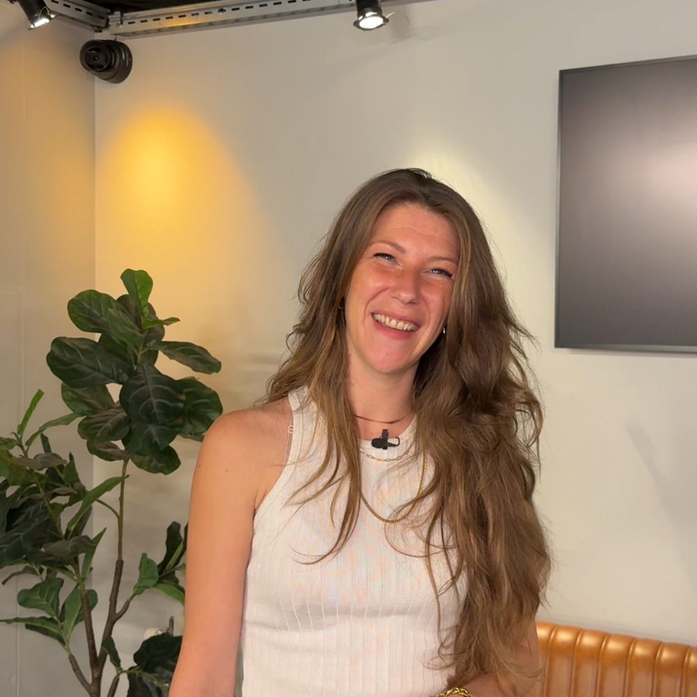 Foto van Nikki, waar dit artikel over gaat. Ze kijkt lachend de camera in. Zee heeft lang haar wat ze los draagt.