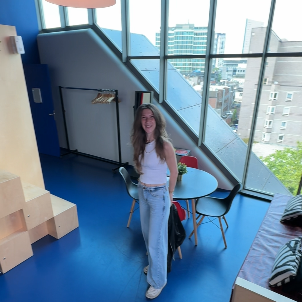 Foto van Nikki in de kleedkamer. Je ziet haar ten voeten uit in een kleedkamer met grote ramen en een blauwe vloer.