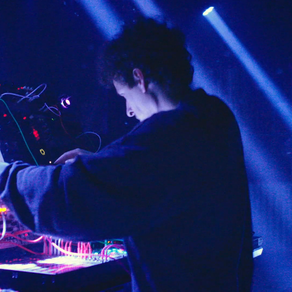 Een dj aan het werk op een blauw-verlicht podium