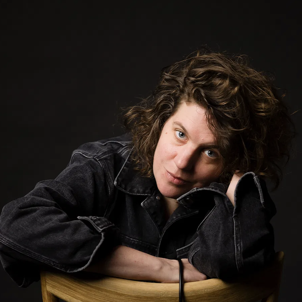 Kim Schuddeboom kijkt in de camera, leunt naar voren