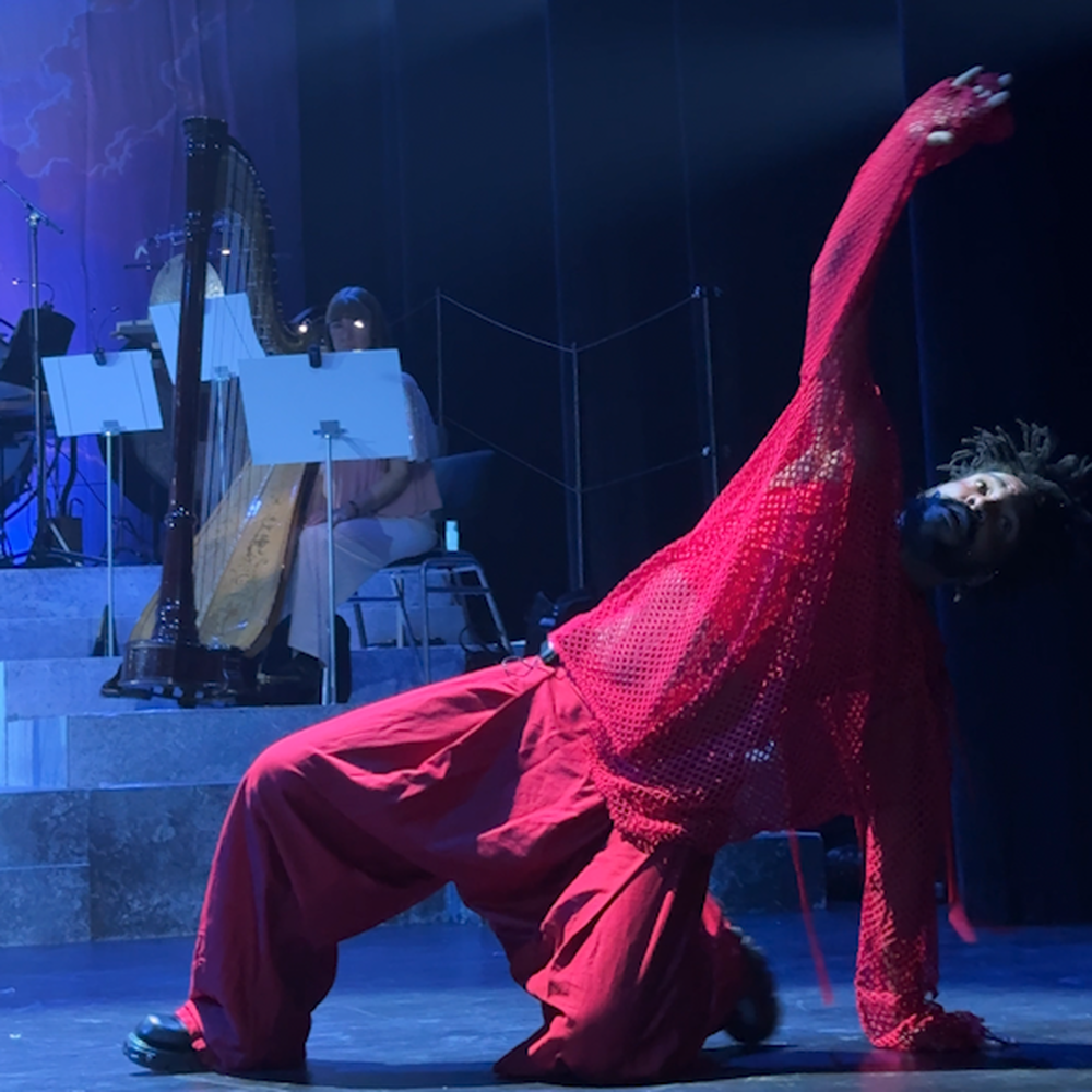 je ziet 1 acteur van kleur met de grijze ijzeren hamer van Thor, de Noorse god. hij vertolkt de rol van Loki in oranje en rode gewaden.