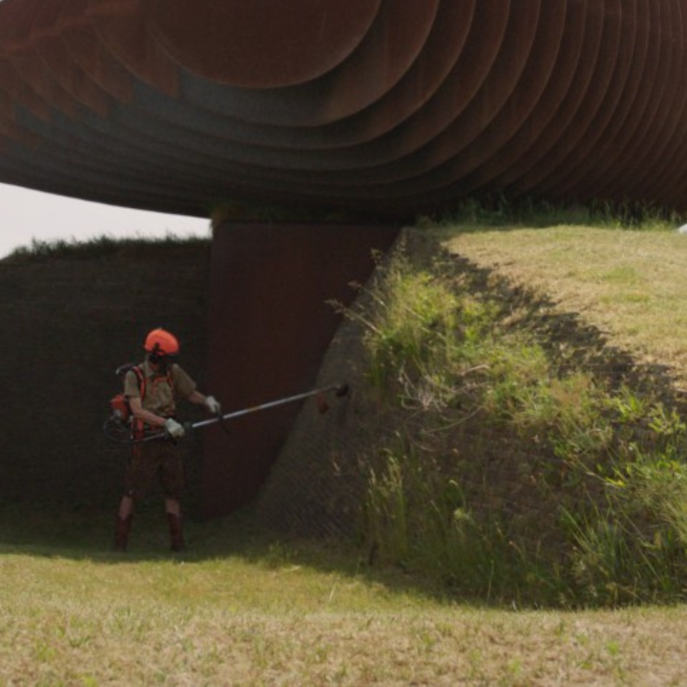 Een groot kunstwerk en een man met een grasmaaier