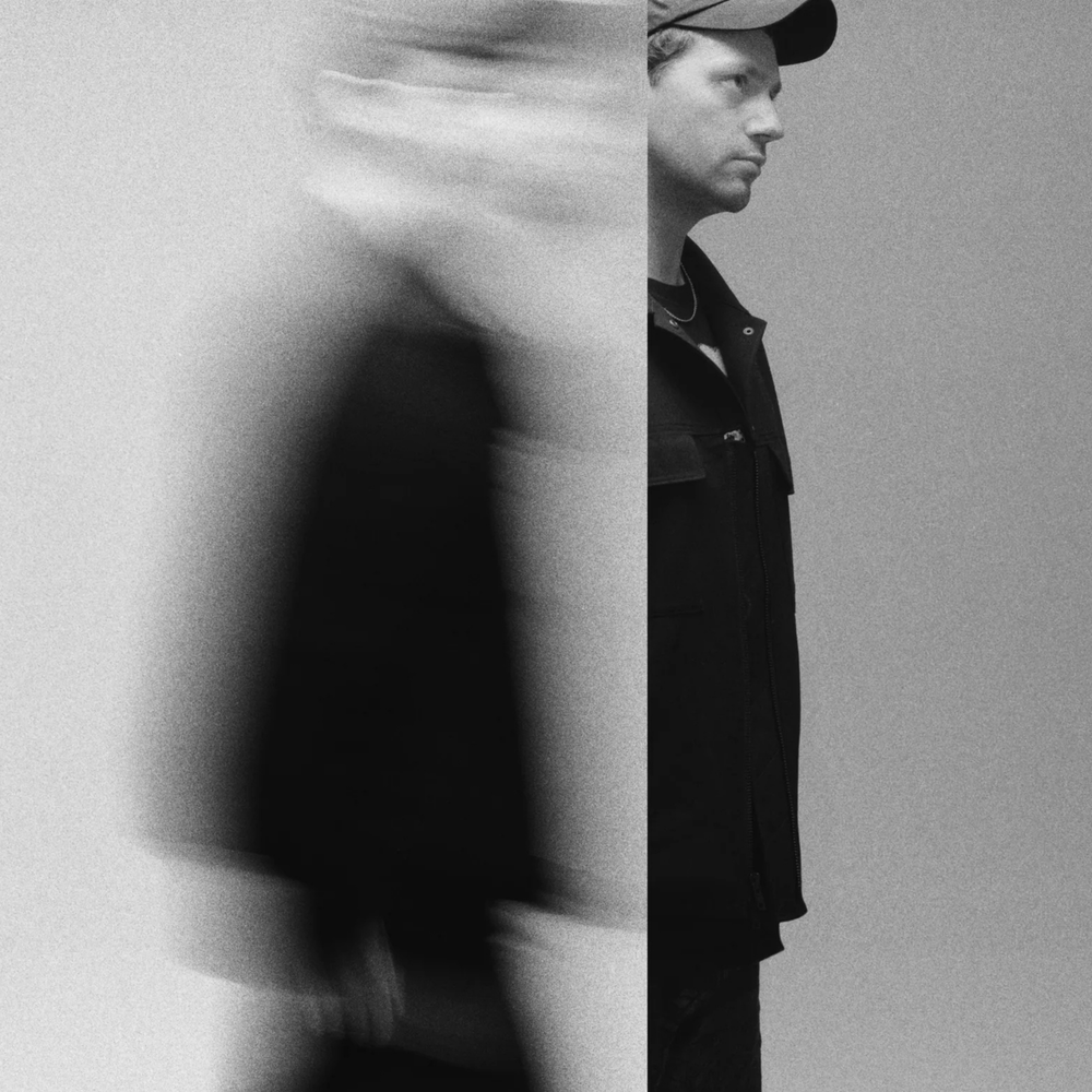 Een foto van Young Marco. Een man met een petje en hij kijkt naar de zijkant. Je ziet hem ten voeten uit.