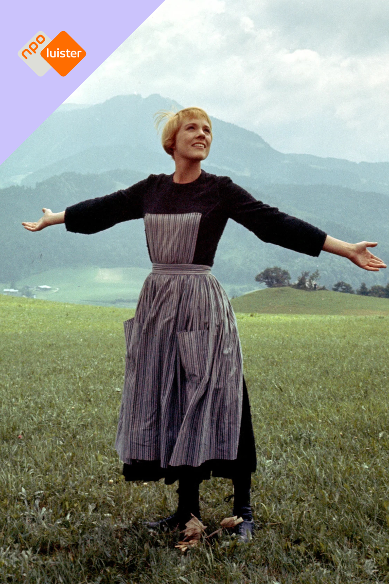 Witte mevrouw in een jurk staat blij met haar armen gespreid op een berg